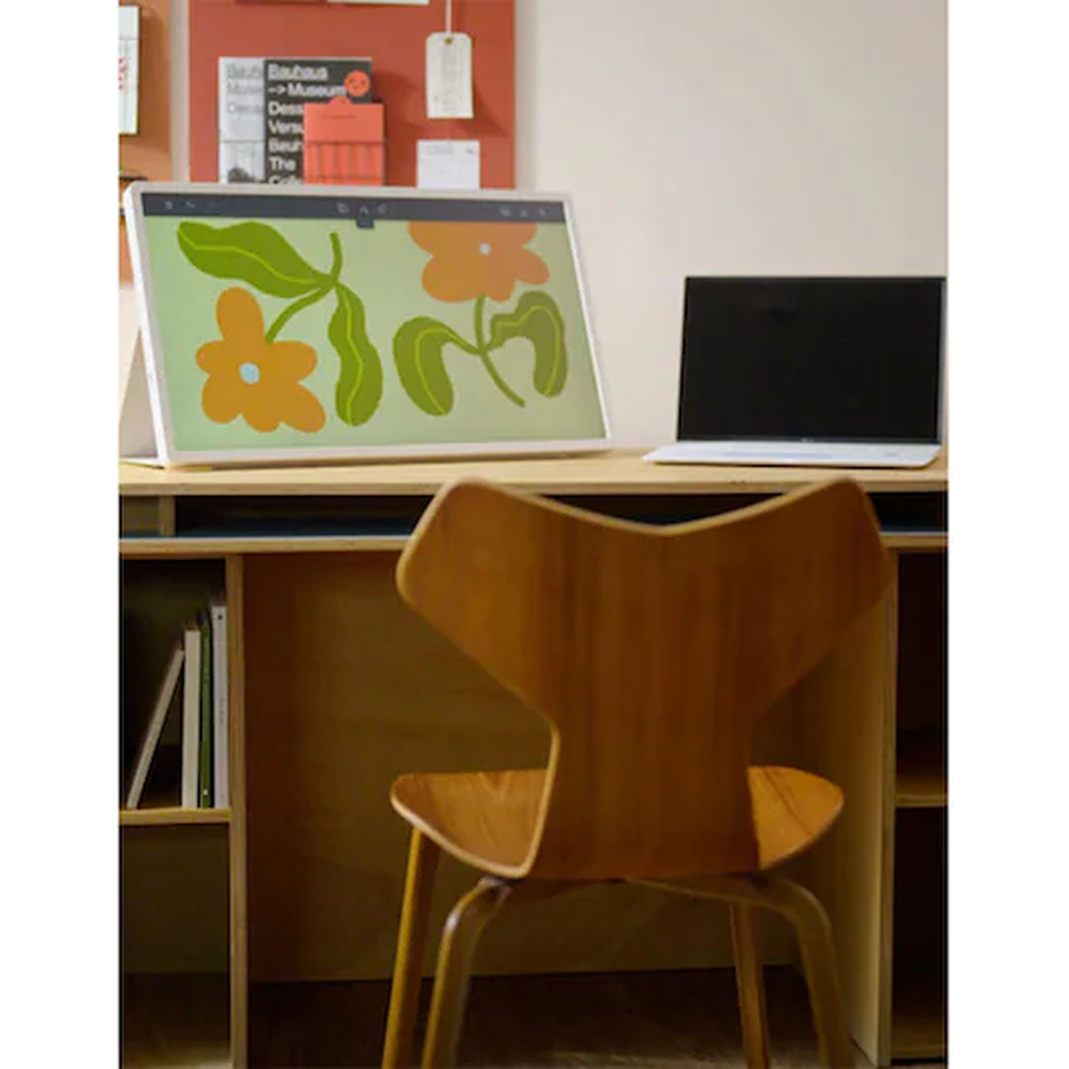 Een bureau met digitale kunstweergave en laptop, een houten stoel ervoor.