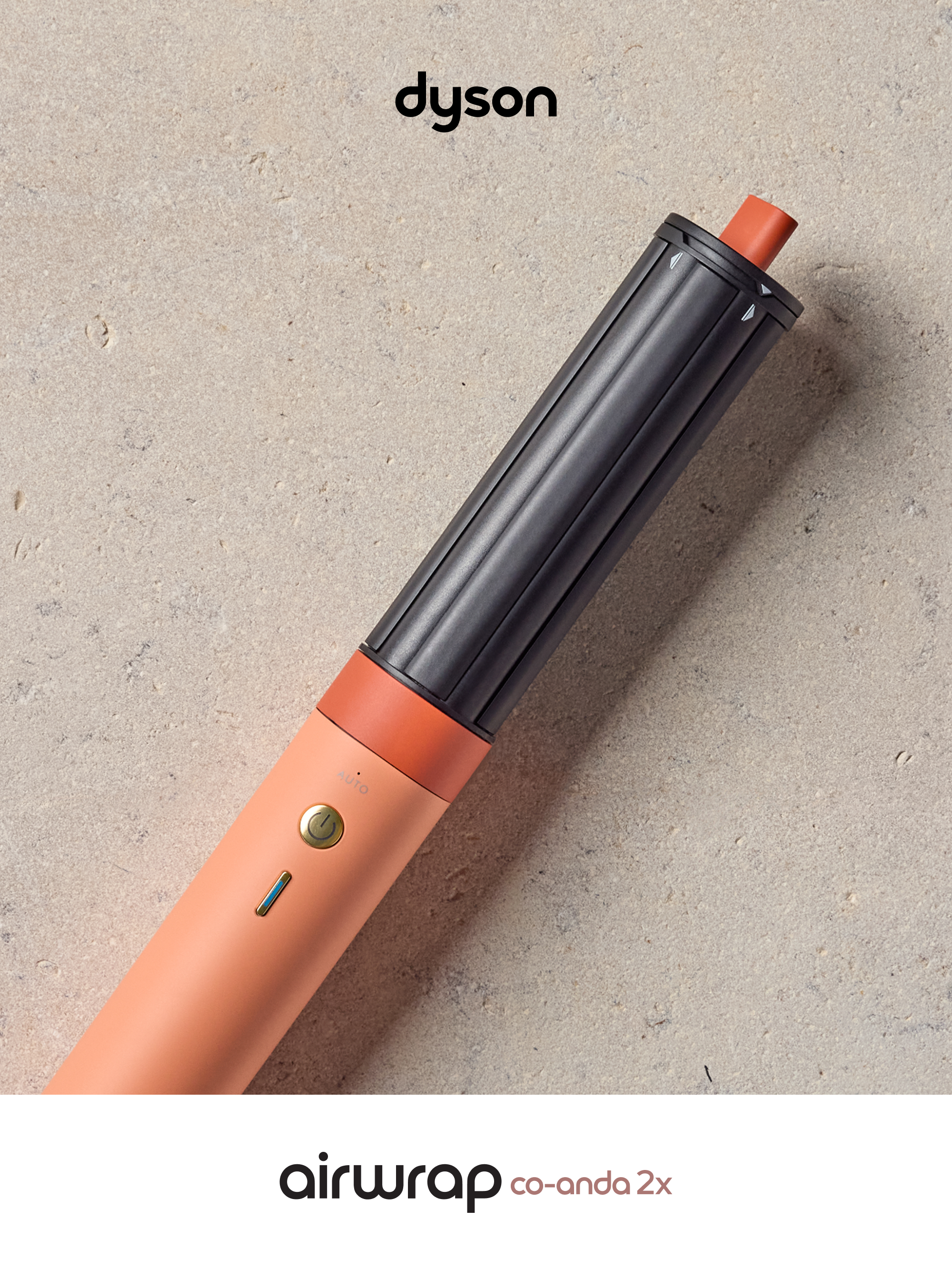 Mercan renkli namlu ve siyah silindirli Dyson Airwrap taş üzerinde duruyor.