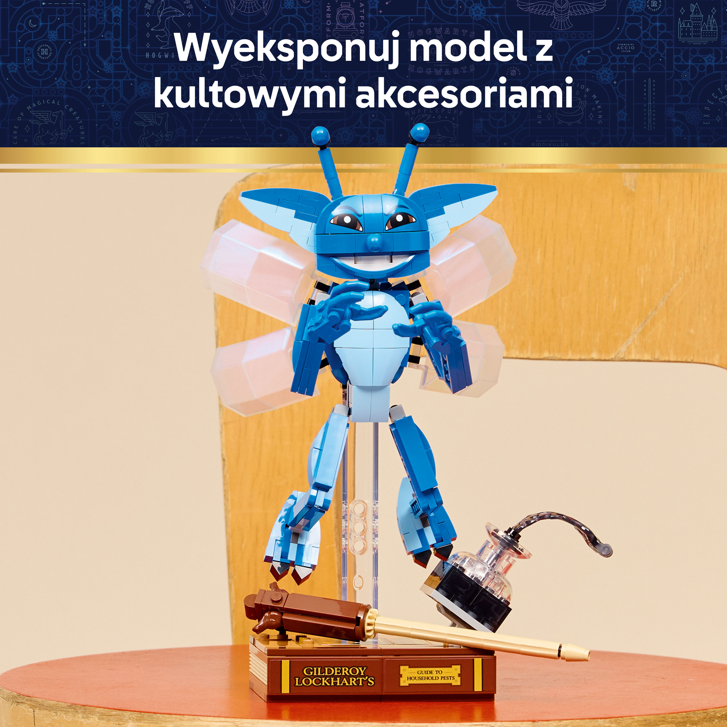 Niebieska postać z LEGO ze skrzydłami stoi na książce, obok pióra i kałamarza.
