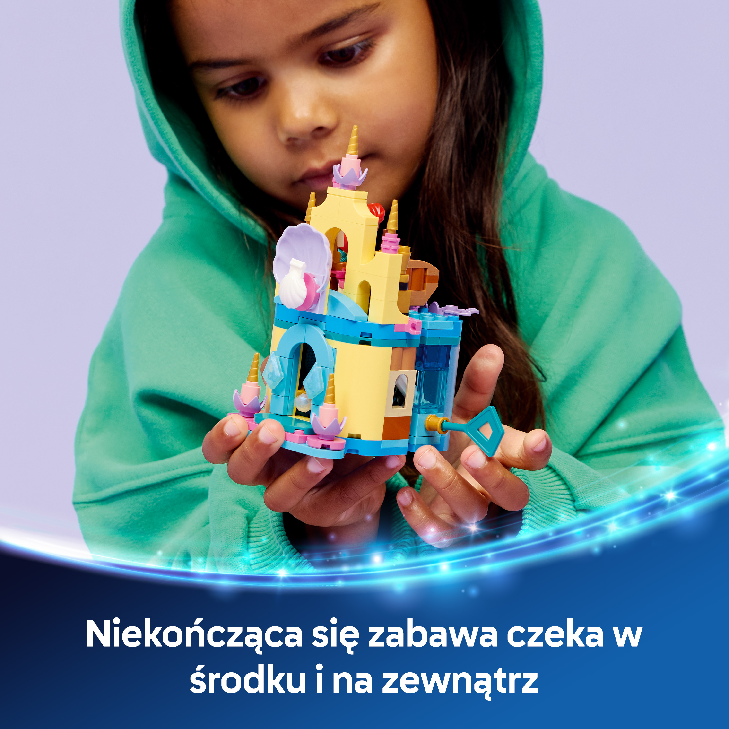 Dziewczynka trzyma kolorowy zamek z klocków.