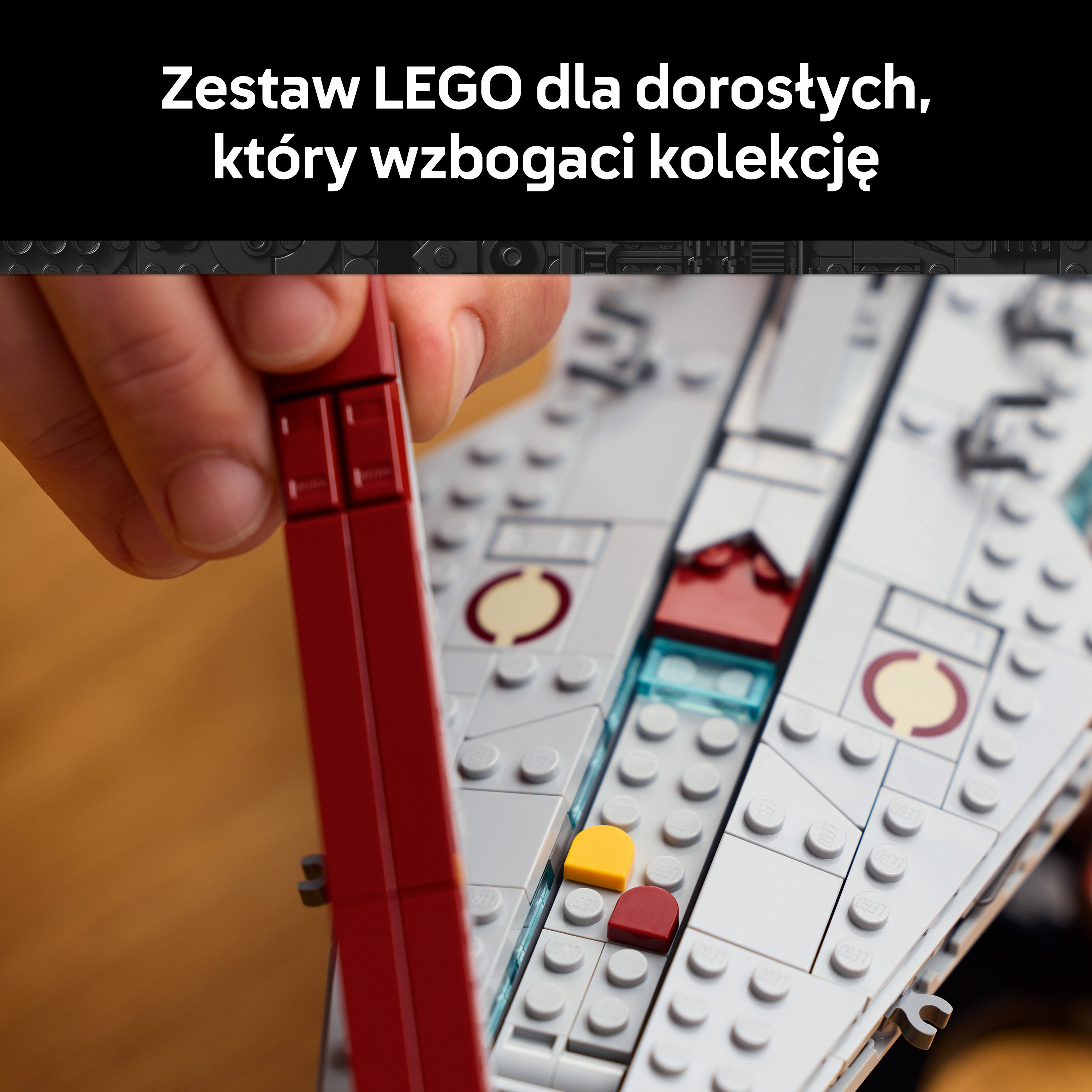 Dłoń umieszcza czerwoną cegiełkę LEGO na białym modelu LEGO. Widoczne są małe żółte i czerwone klocki.