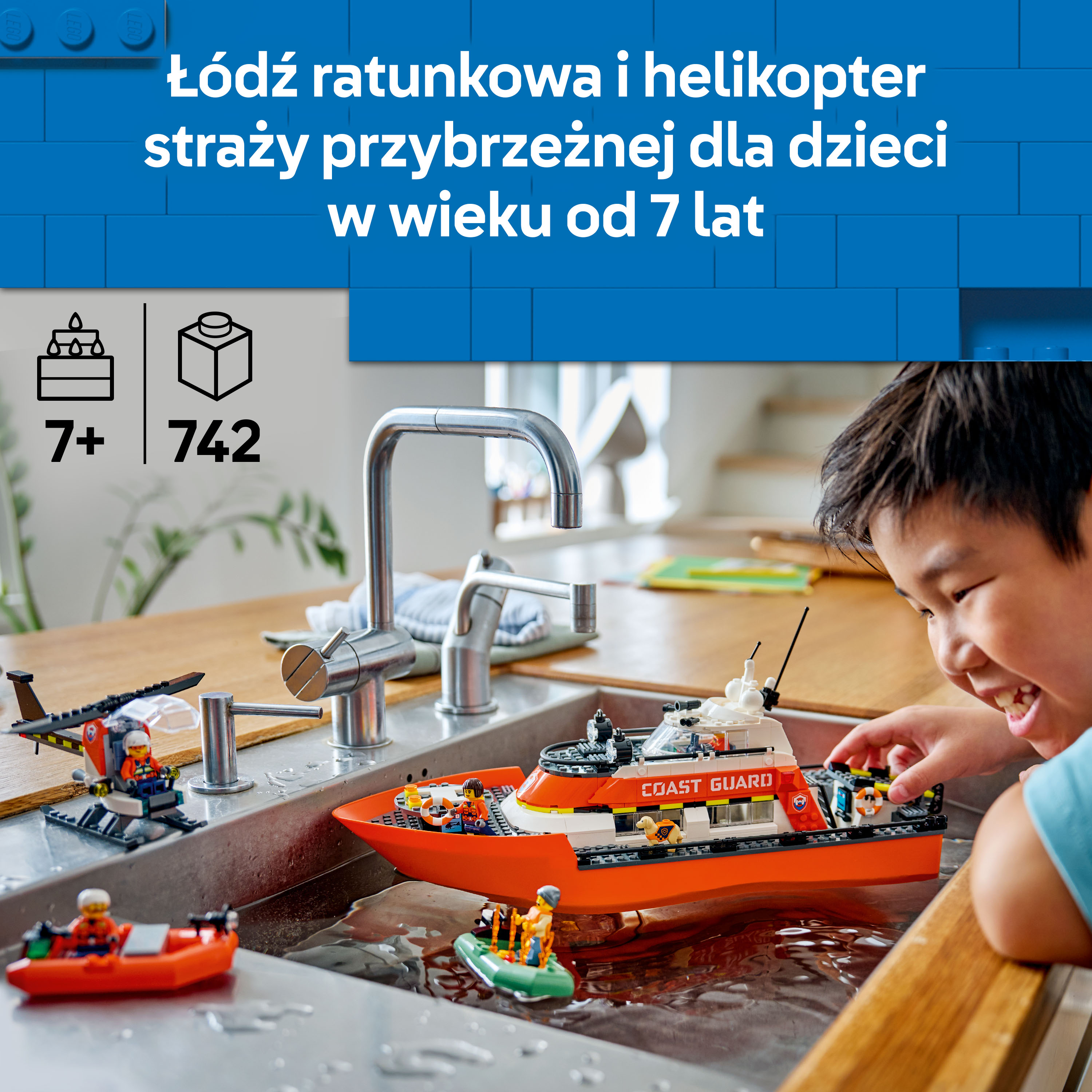 Chłopiec bawi się łodziami i helikopterem Lego w zlewie.