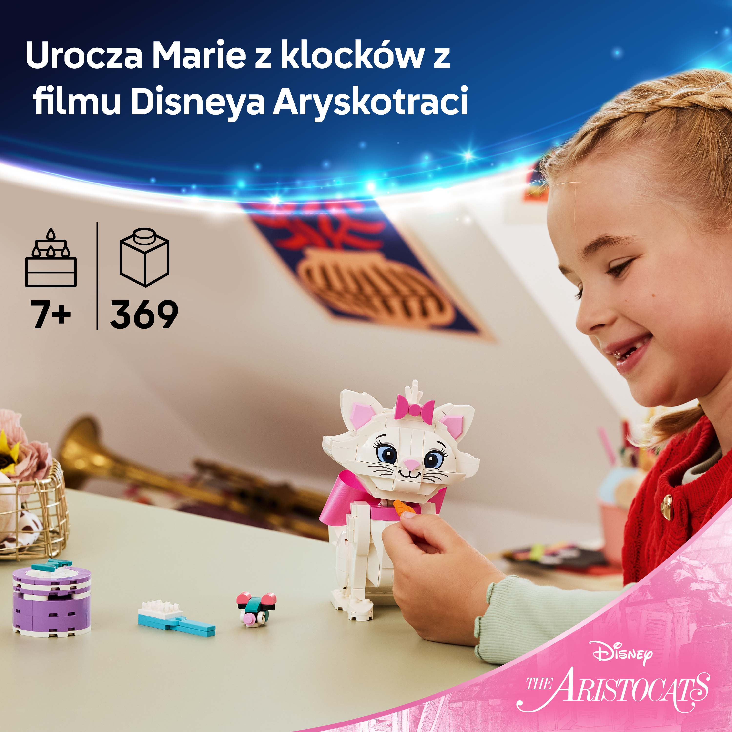 Dziewczynka buduje białego kota z klocków Lego, noszącego różową kokardkę.