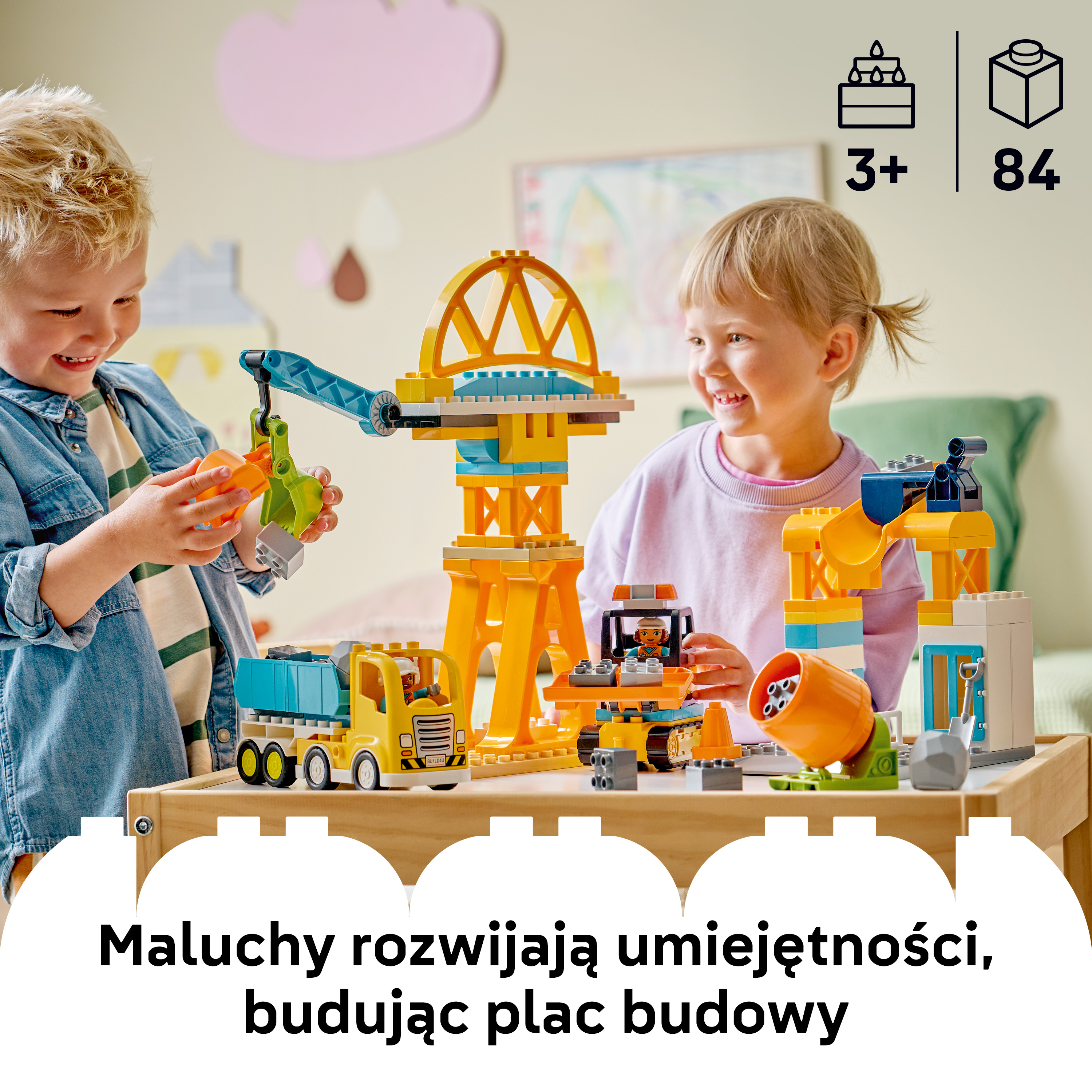Dwoje dzieci buduje plac budowy z kolorowych klocków Lego, ciężarówki z dźwigiem i koparek.