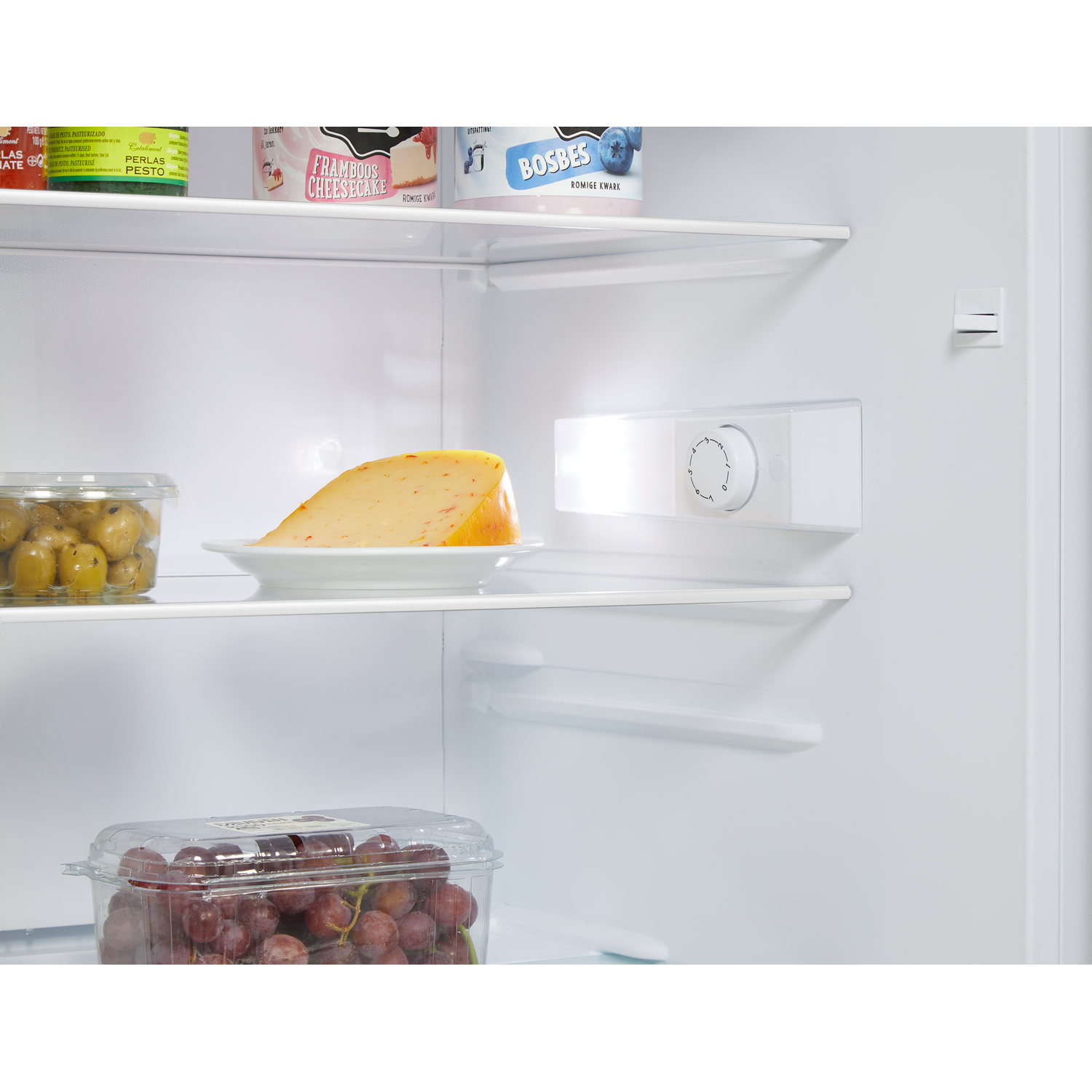 Koelkastinterieur met kaas, olijven, druiven en yoghurtbakjes op planken.