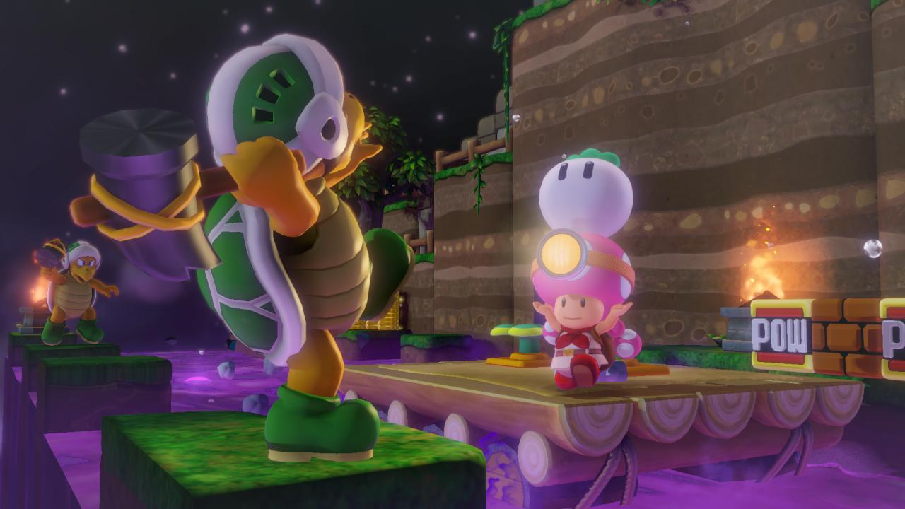 Koopa z młotem staje naprzeciw Toad i Toadette w kosmosie.