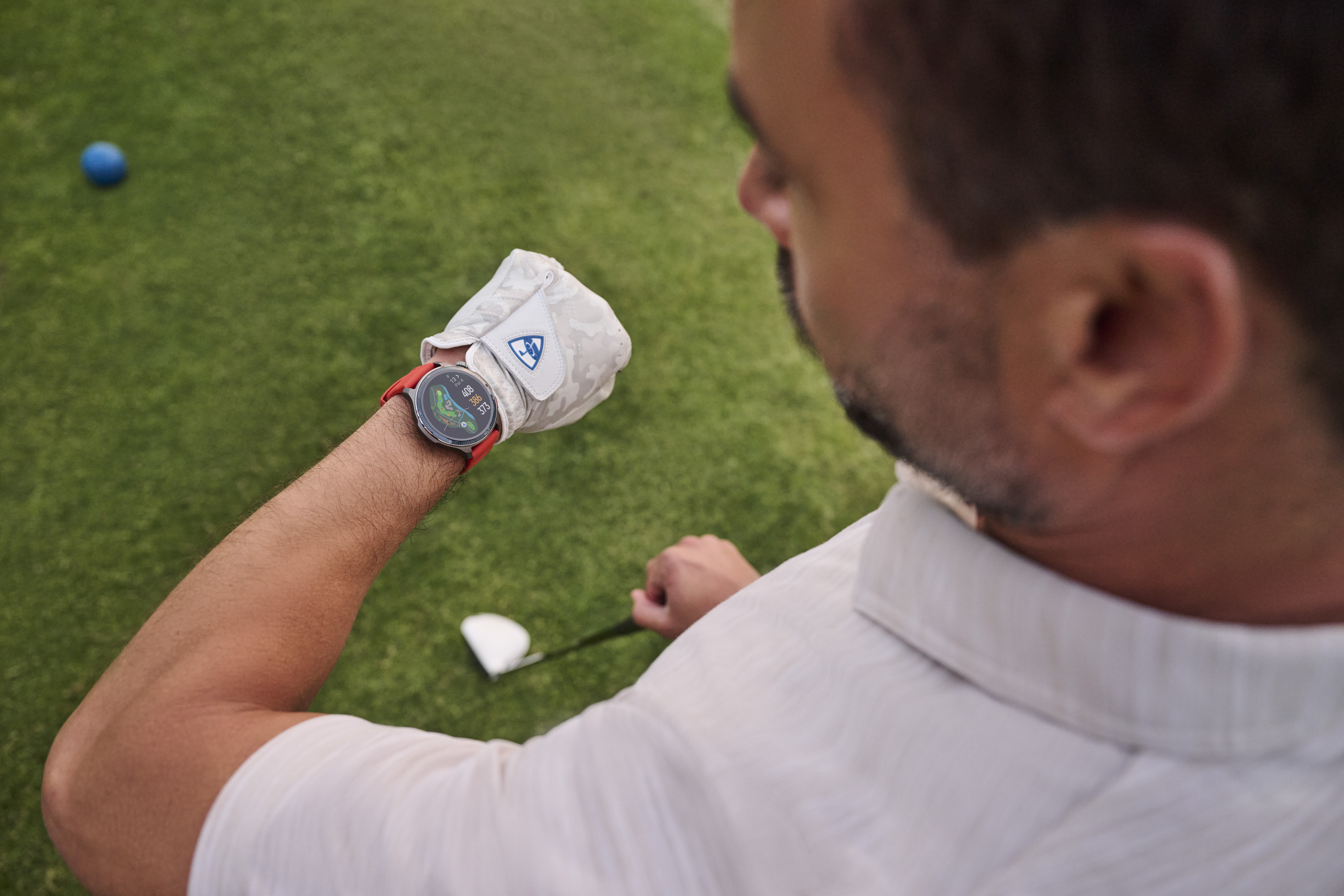 Mężczyzna z zegarkiem i rękawicą golfową na polu golfowym.