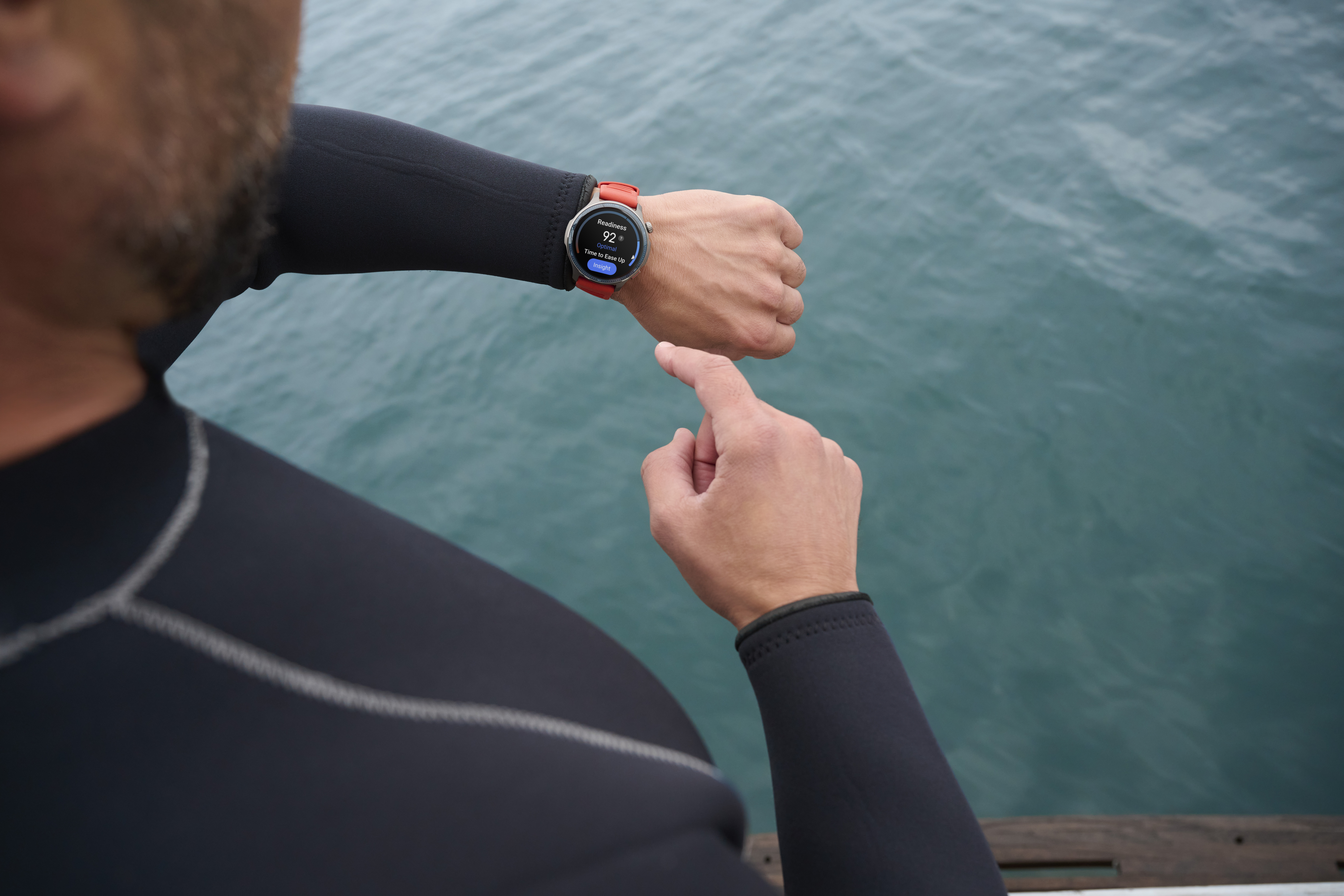 Mężczyzna w czarnym piance sprawdza smartwatch z czerwoną opaską.