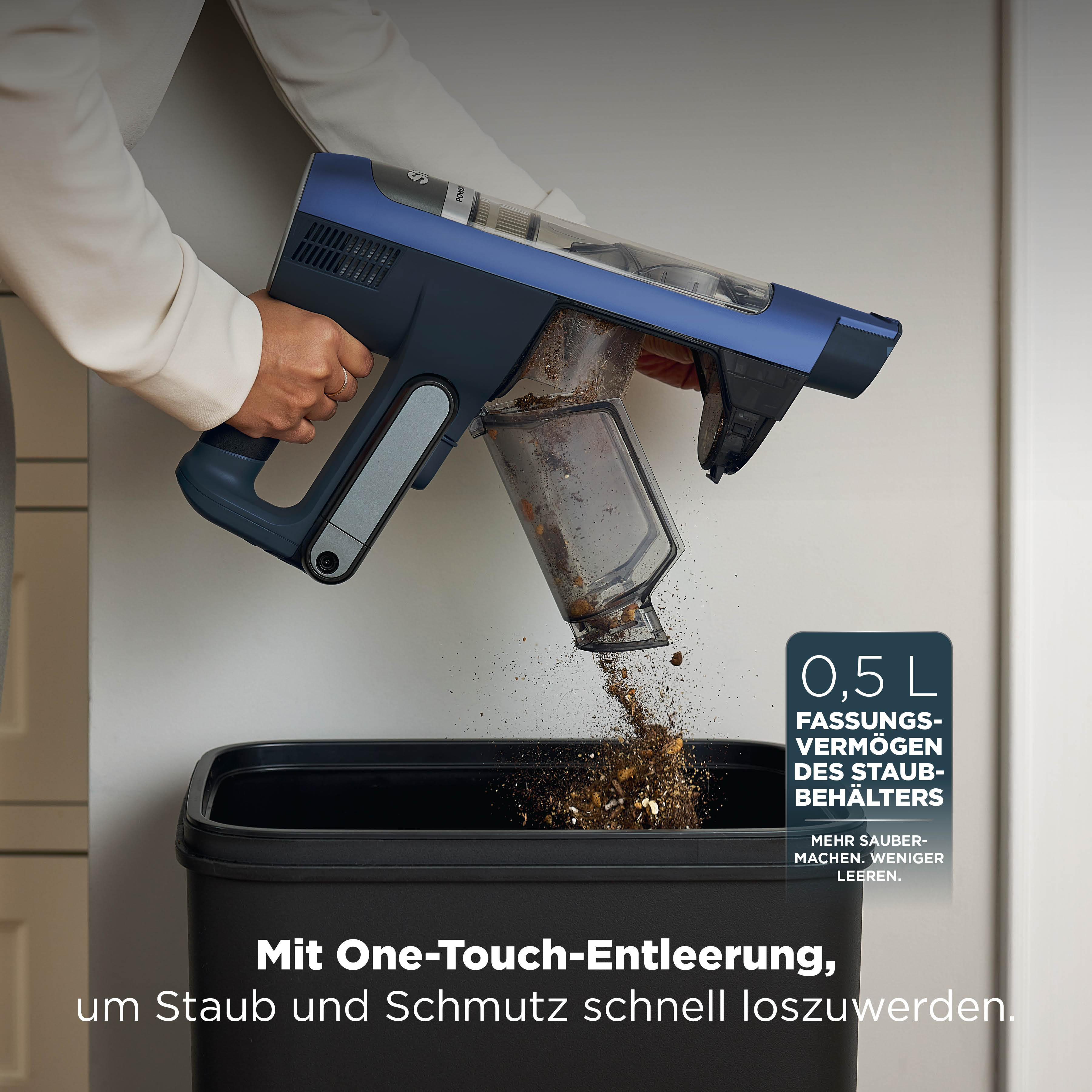 Ein blauer Staubsauger entleert Schmutz in einen schwarzen Behälter.