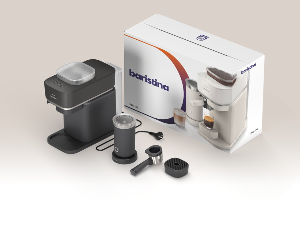 Una cafetera oscura, espumador de leche y accesorios junto a una caja de producto.