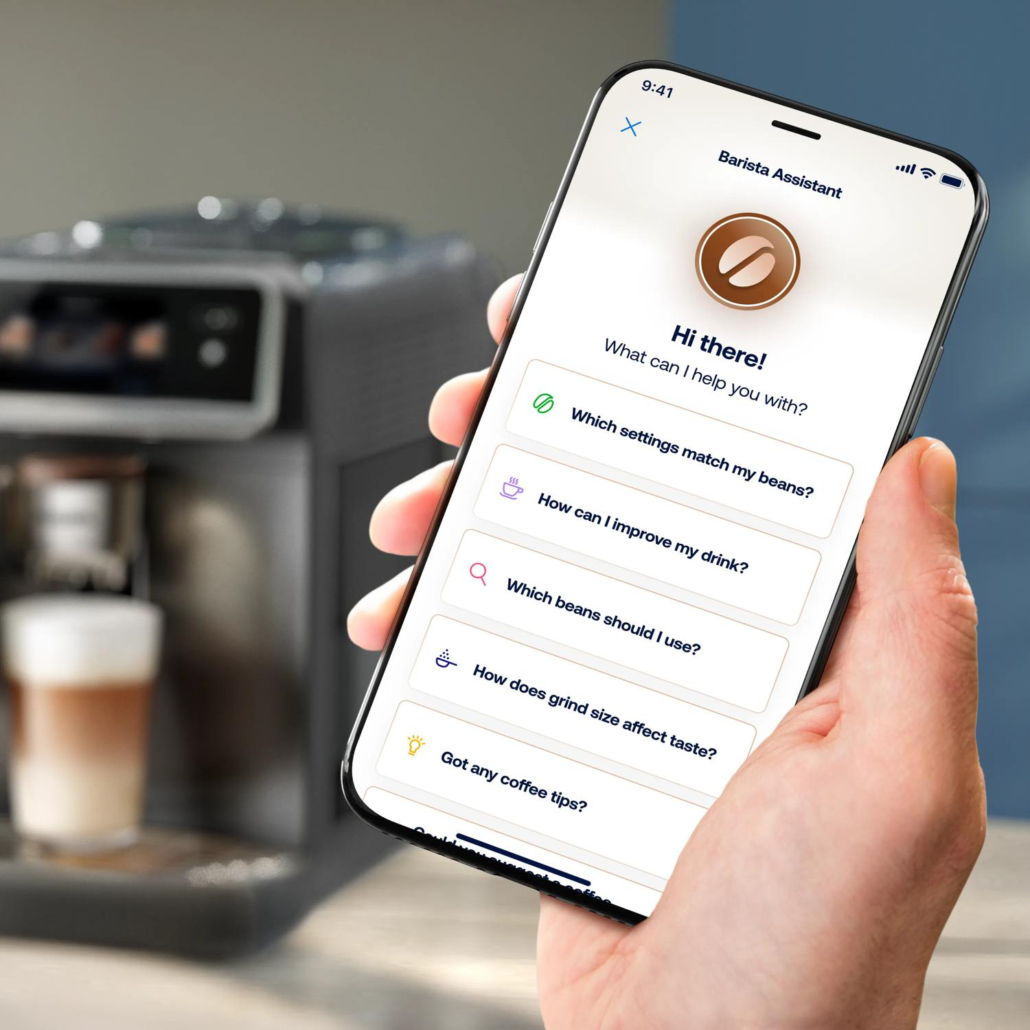 Una mano sostiene un smartphone que muestra una app de Barista Assistant con preguntas sobre café.