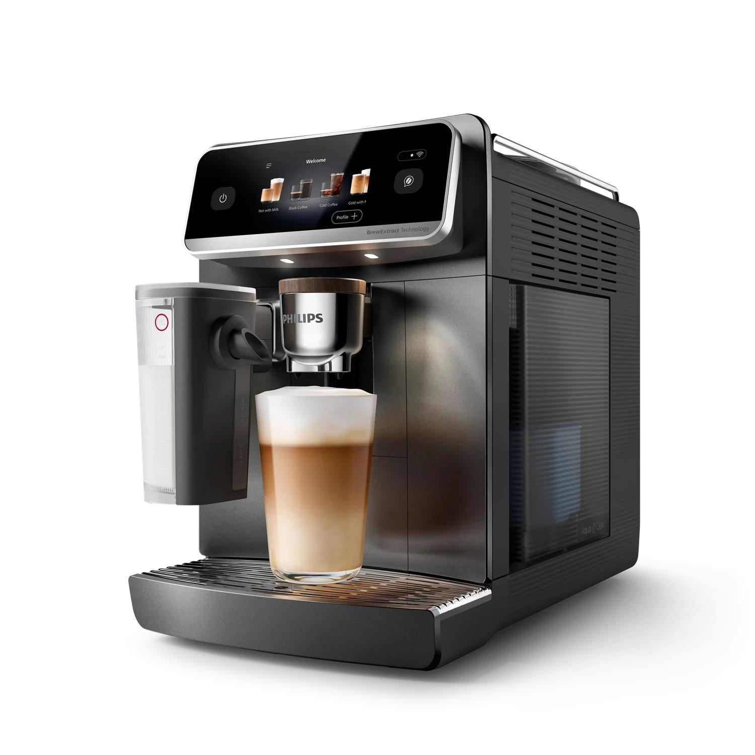 Máquina de café con un vaso de café y espuma de leche, un recipiente de leche al lado.