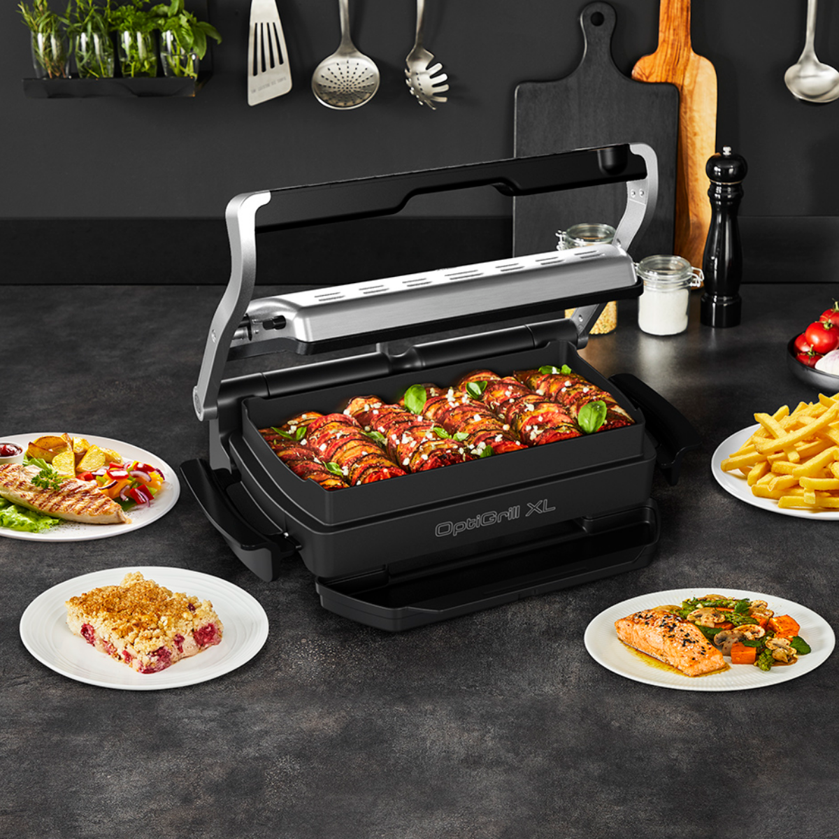 Egy fekete OptiGrill XL, benne étellel fő, ételeket tartalmazó tányérokkal körülvéve.