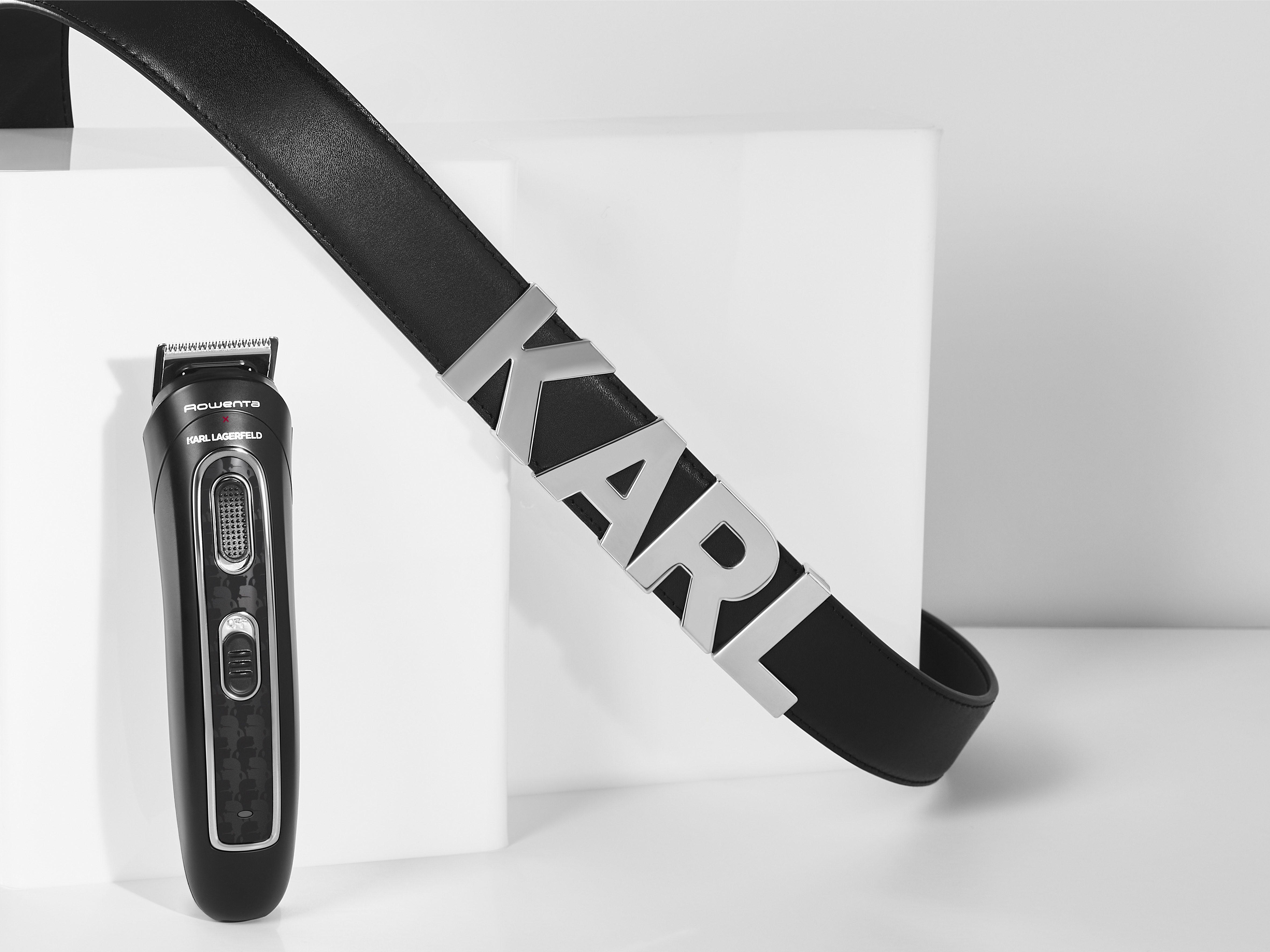Fekete Rowenta Karl Lagerfeld borotva ezüst betűs fekete bőröv mellett.