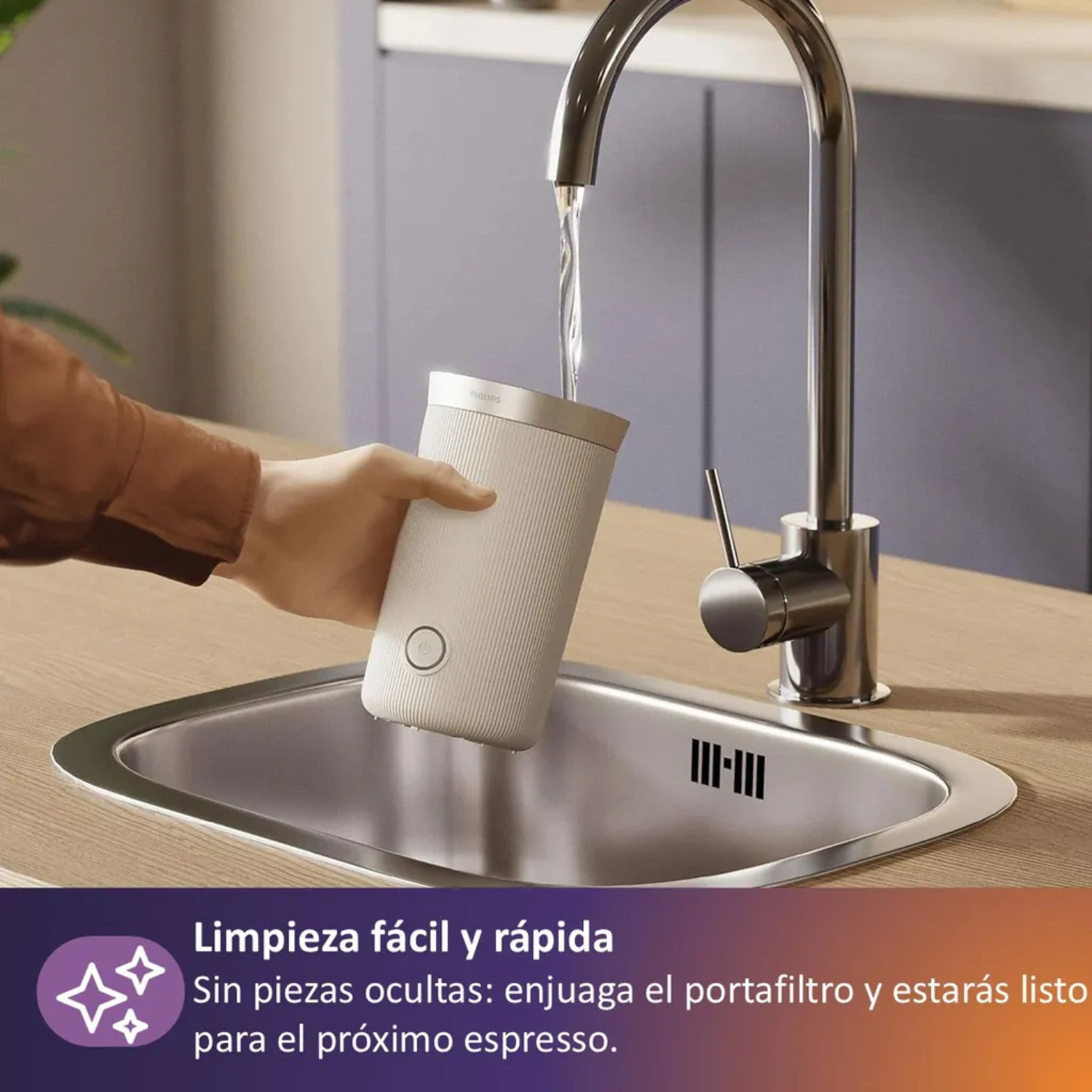 Una mano enjuaga un portafiltros blanco bajo agua corriente en un fregadero.