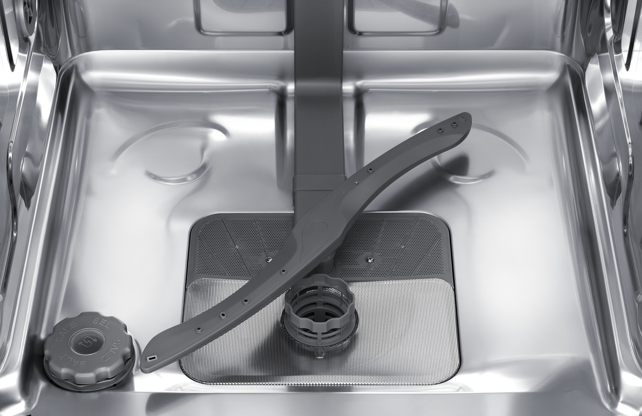 Wnętrze zmywarki z ramieniem natryskowym, pojemnikiem na sól i filtrem.