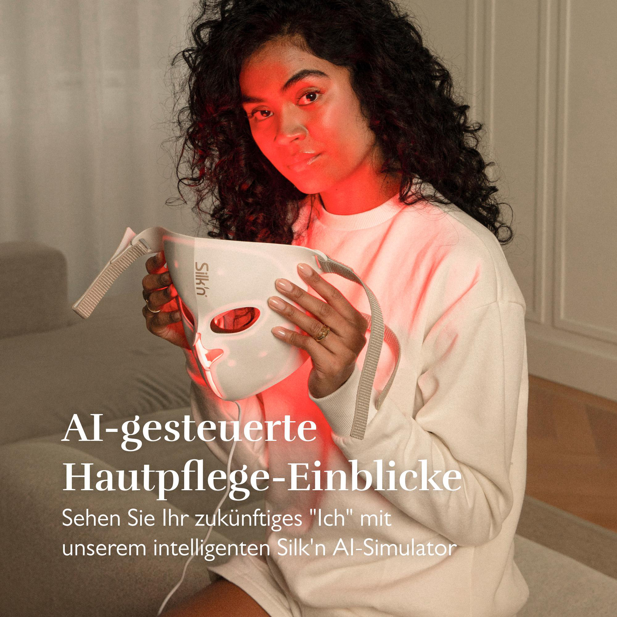 Eine Frau hält eine weiße Gesichtsmaske vor sich, die mit rotem Licht beleuchtet ist.