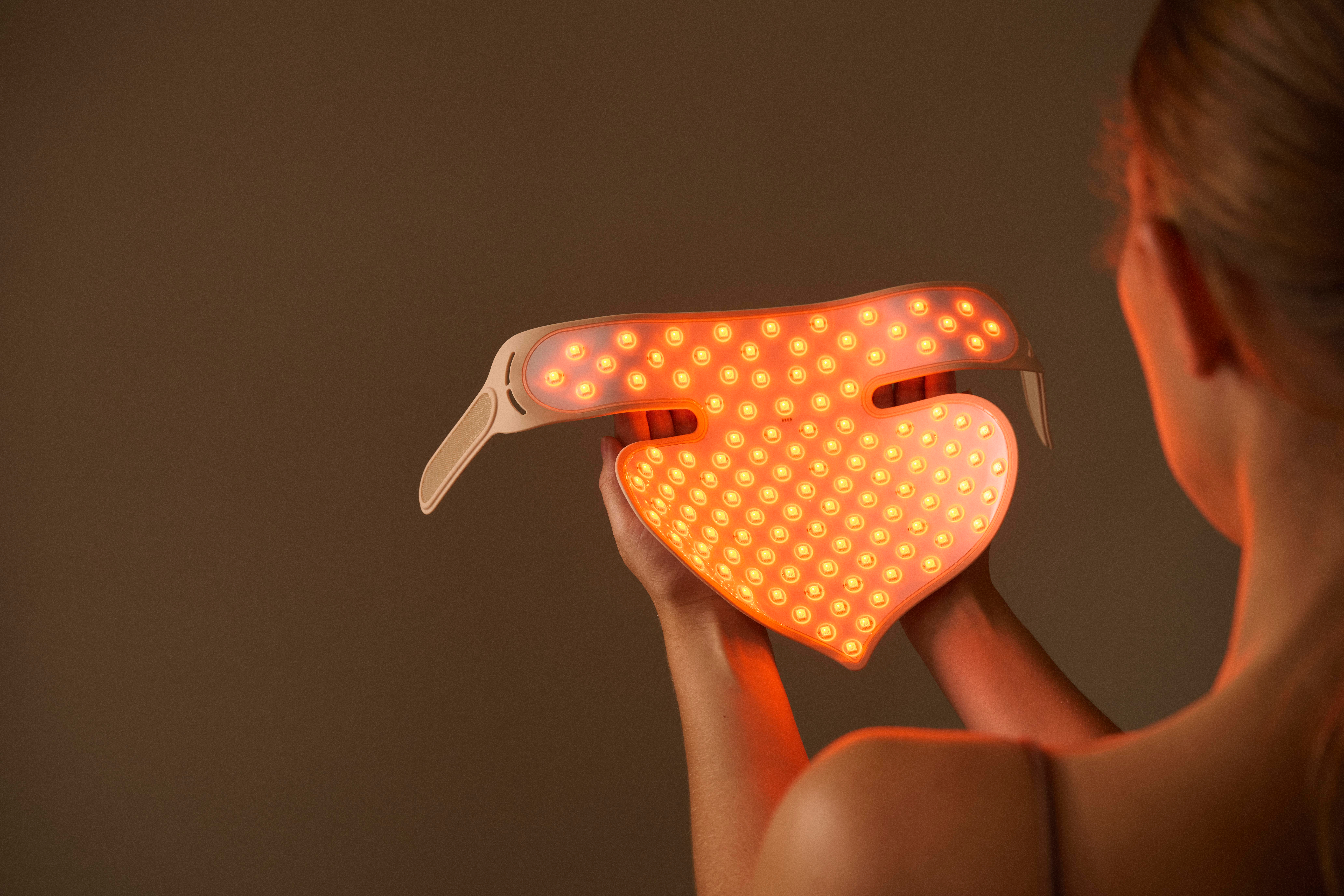 Eine Person hält eine herzförmige Maske mit Lichtern.