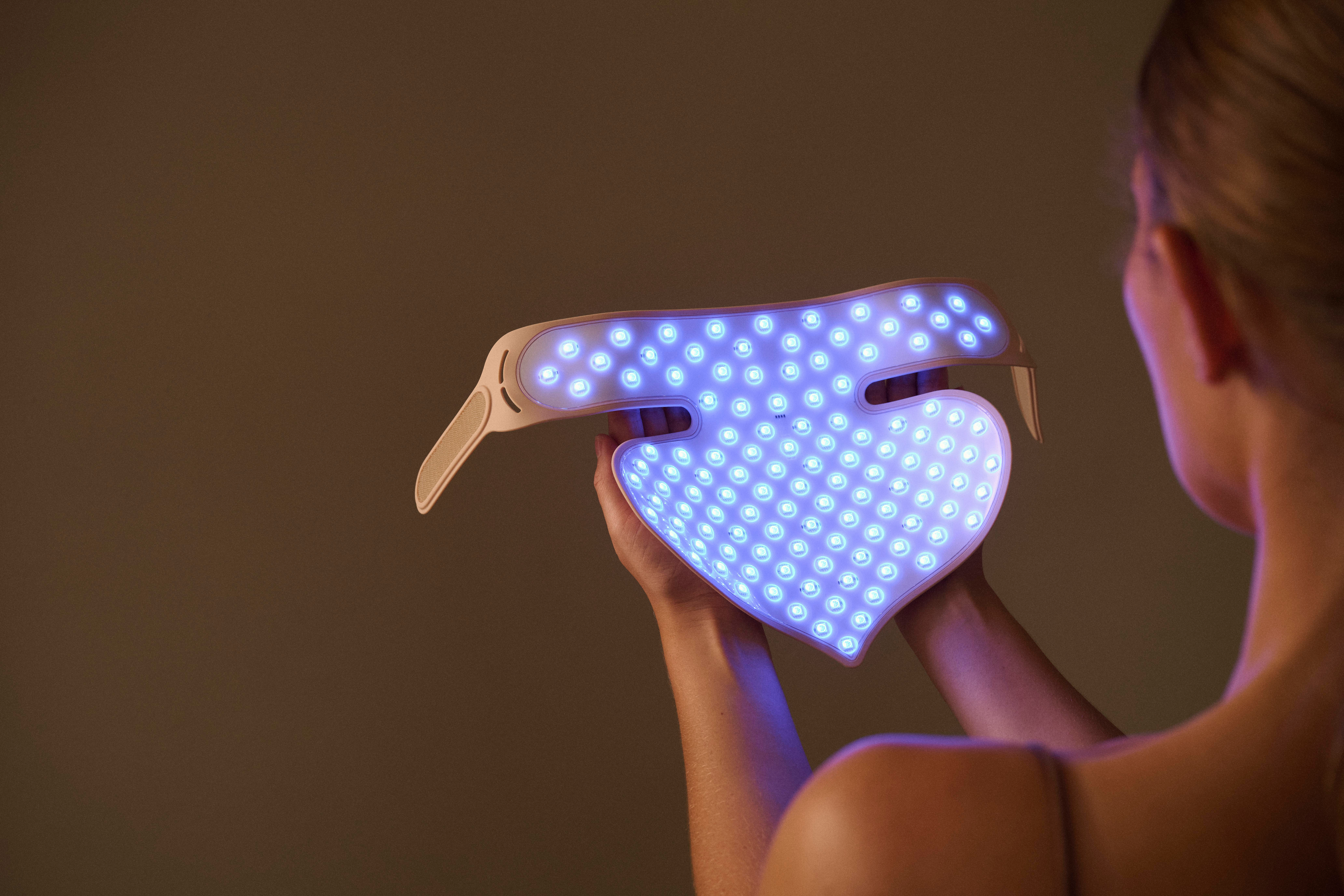 Eine Person hält ein Herz-förmiges Gerät mit blauen LEDs in Händen.