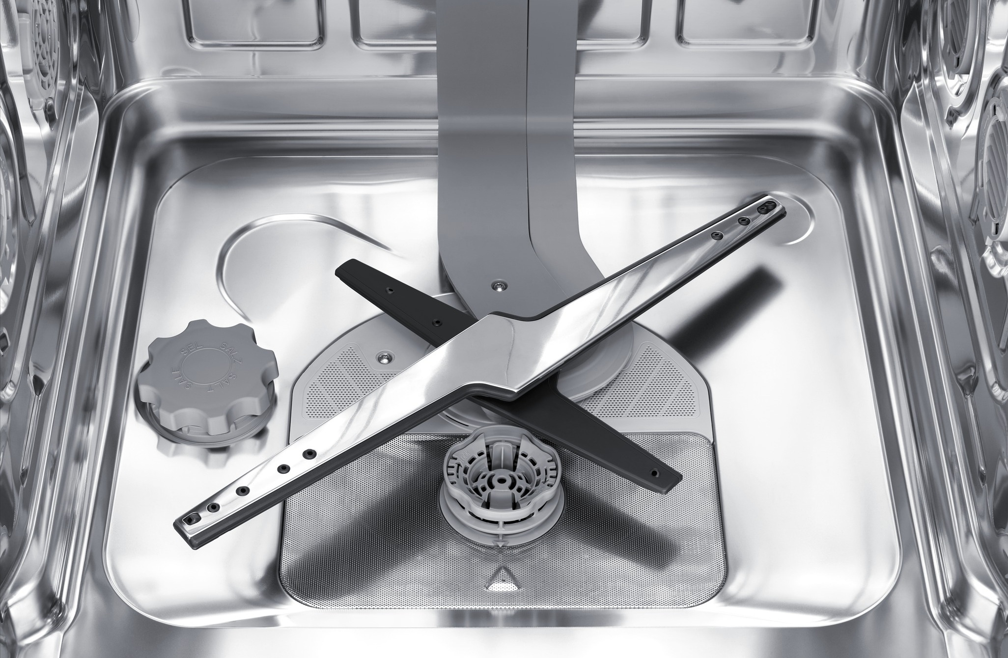 Widok wnętrza zmywarki z ramionami natryskowymi i pokrywą pojemnika na sól.