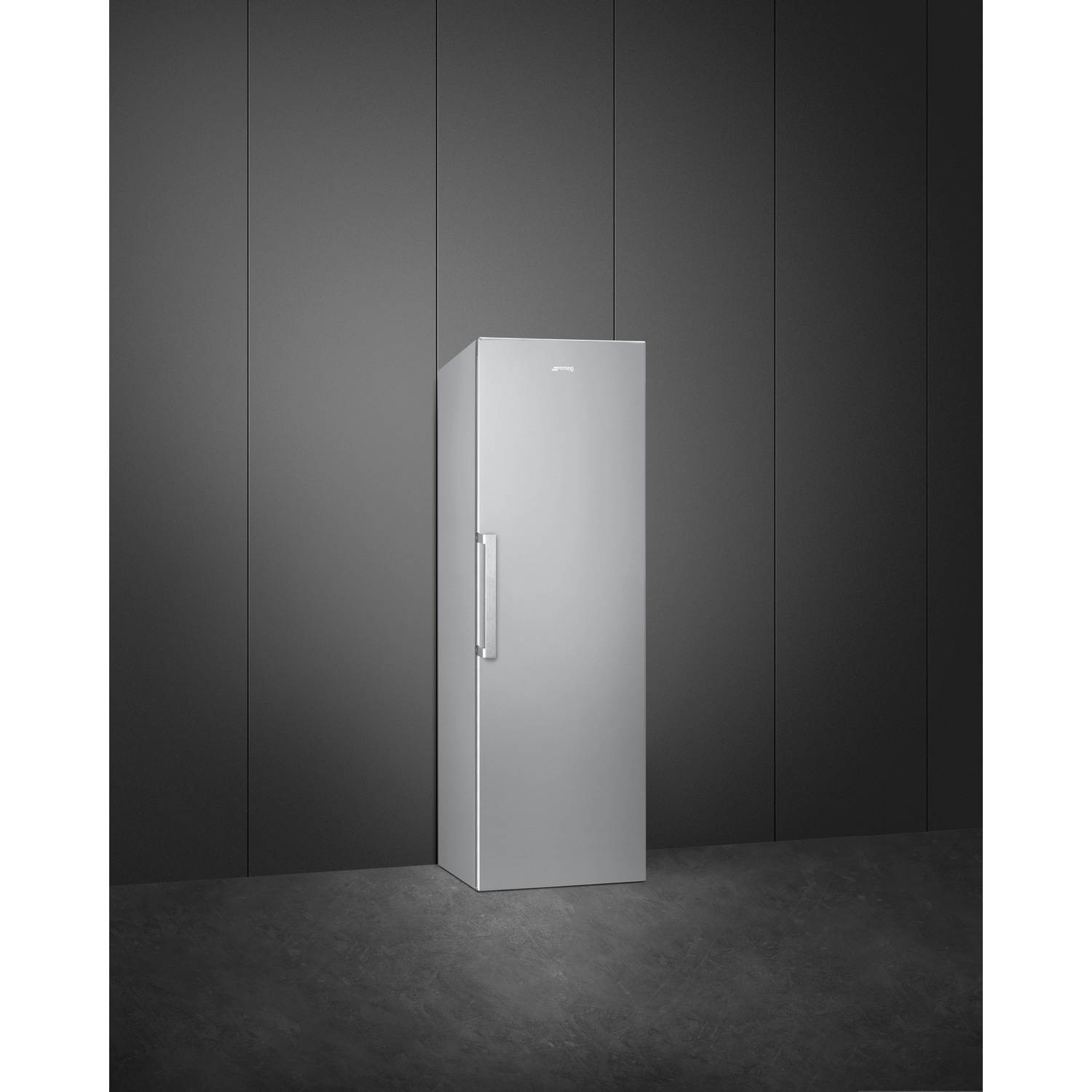 Un frigorifero argento freestanding con maniglia davanti a una parete scura.