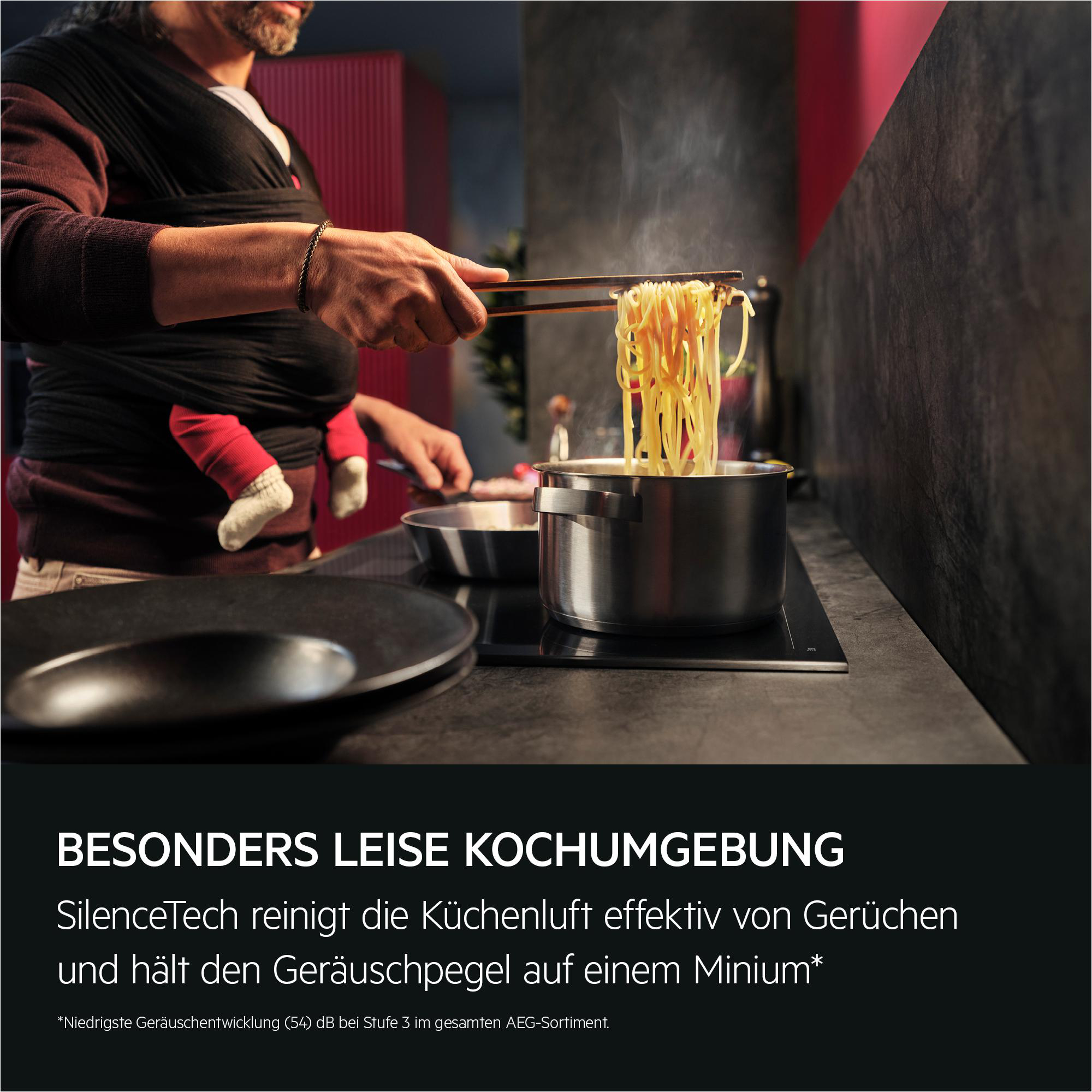Ein Mann mit Baby im Tragetuch kocht Nudeln in einem Topf.