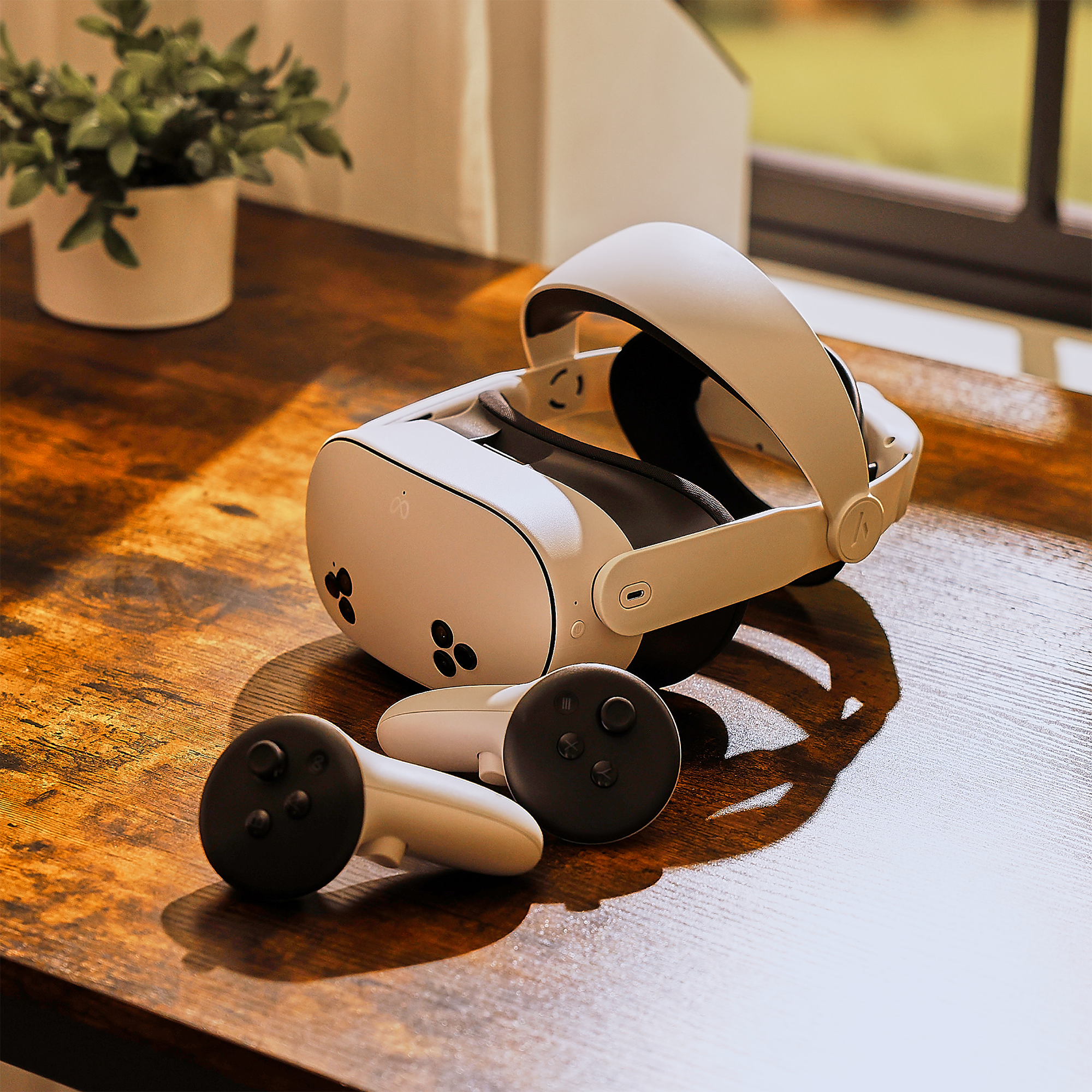 Weiße VR-Brille und Controller auf einem Holztisch mit Sonnenlicht.