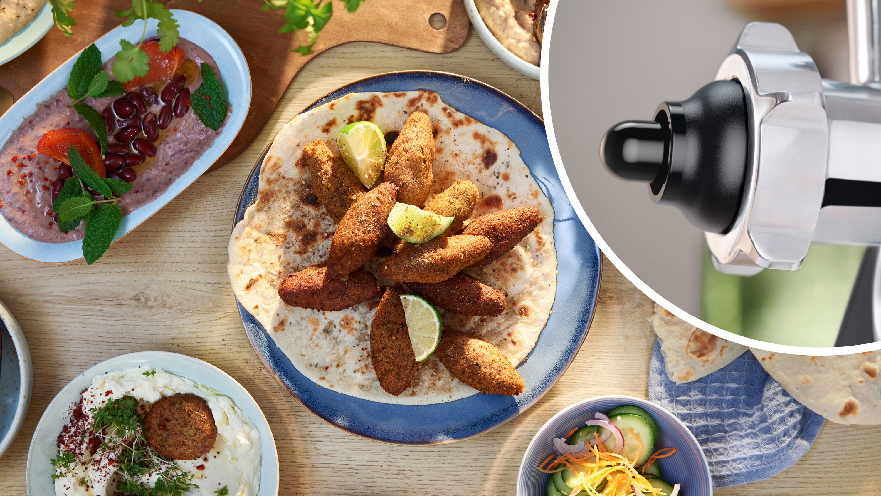 Nahaufnahme von nahöstlichen Gerichten, darunter Hummus, Falafel und Kebab, mit einem Fleischwolf im Hintergrund.