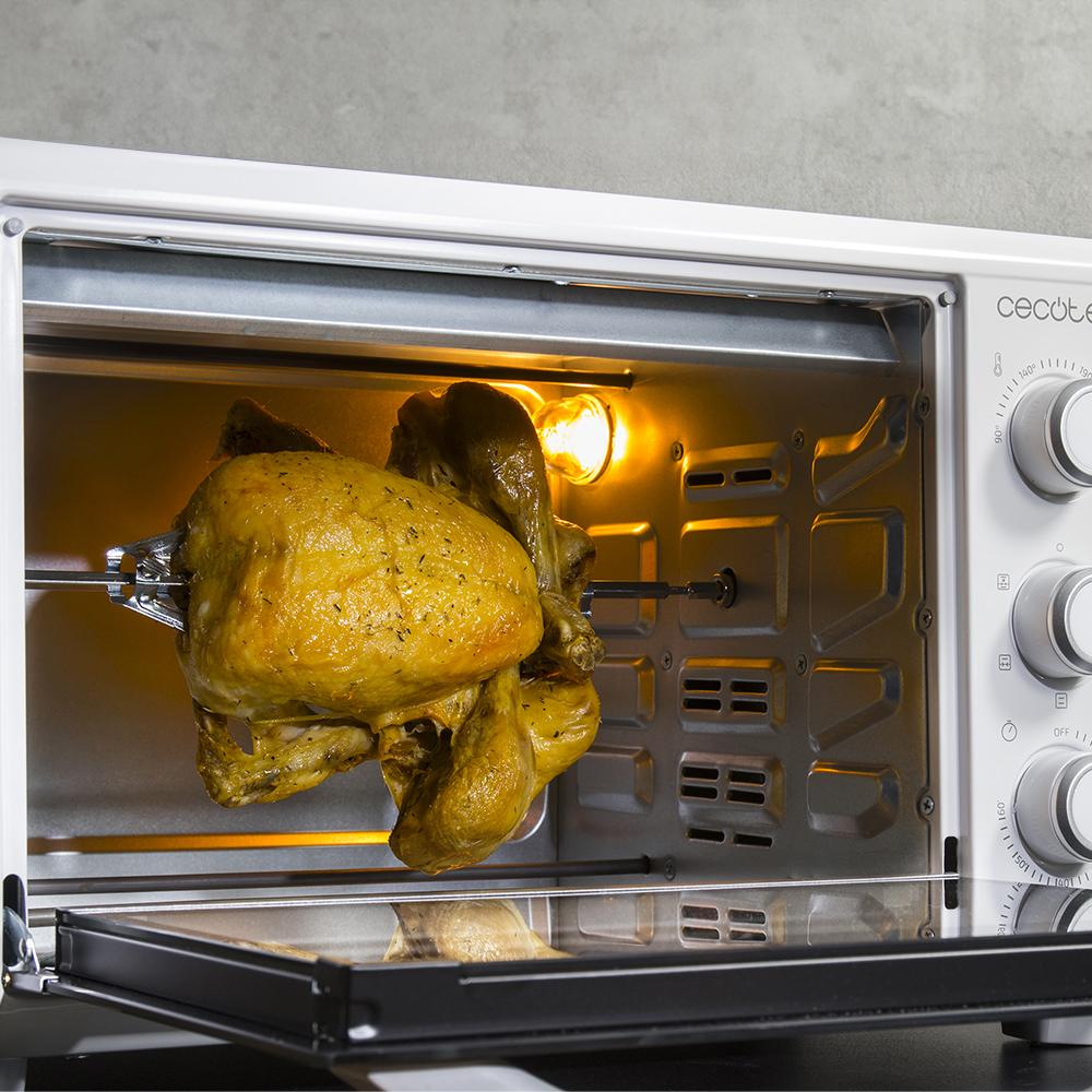 Un pollo dorado gira en un horno sobre un asador.