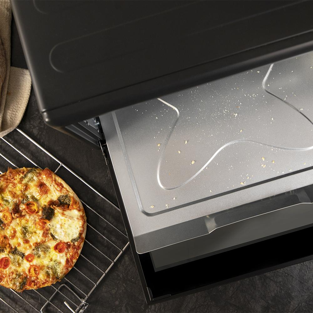 Una pizza en una rejilla junto a un horno negro abierto con migas dentro.