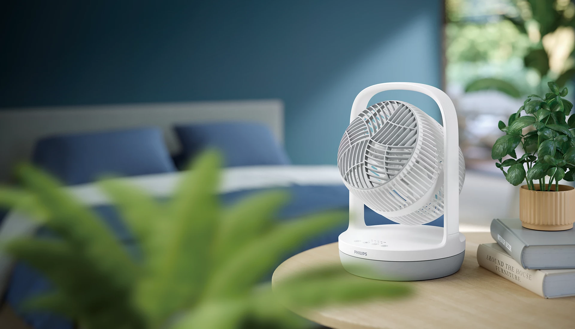 Ein weißer Tischventilator steht auf einem Holztisch vor einem Bett.