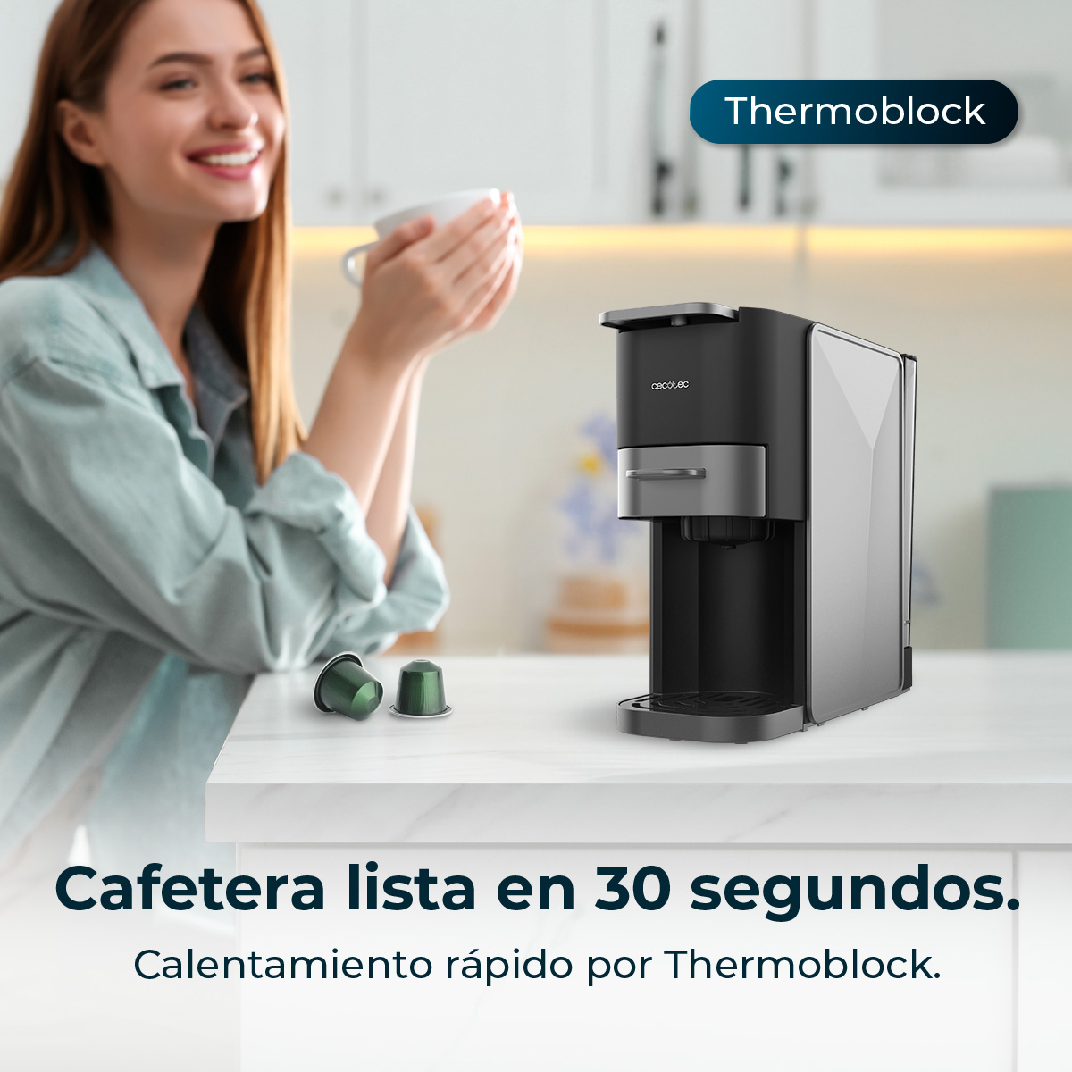 Una mujer bebe café junto a una cafetera moderna y cápsulas.