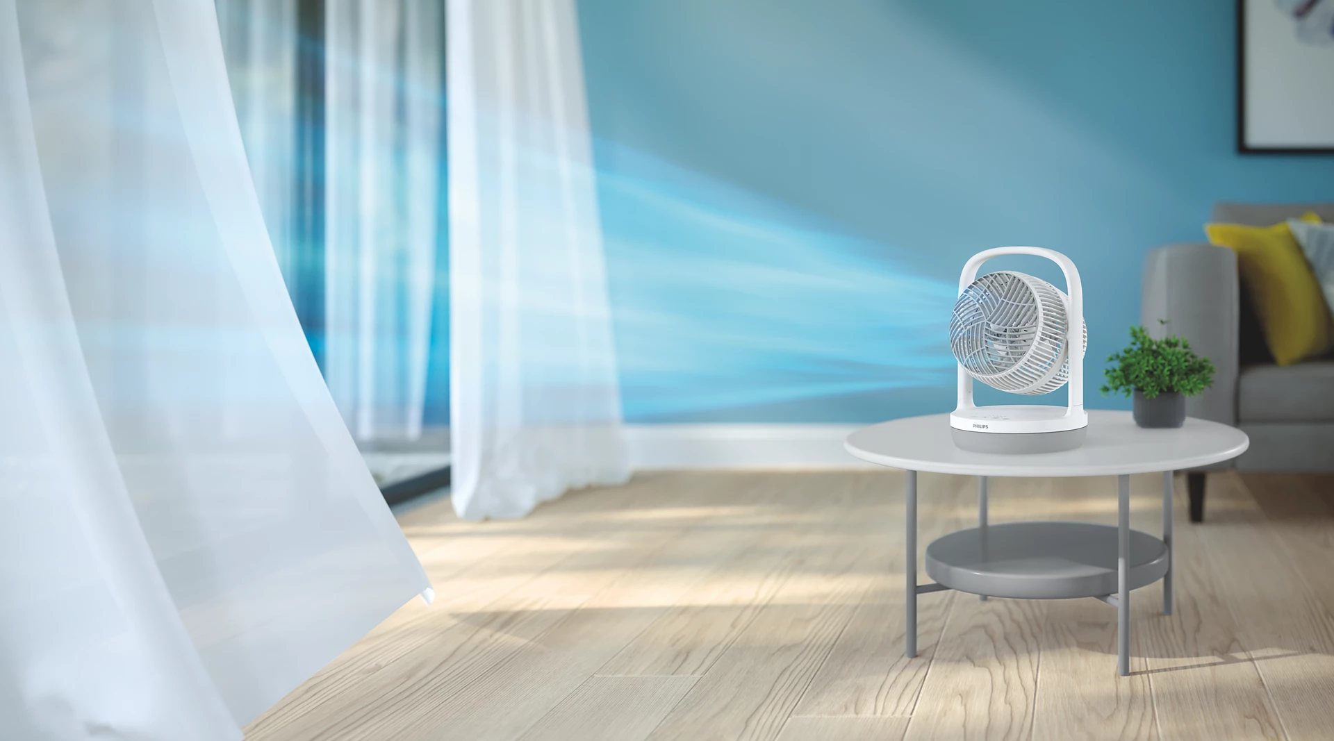 Ein weißer Ventilator auf einem Tisch zirkuliert Luft in einem hellen Raum mit transparenten Vorhängen.