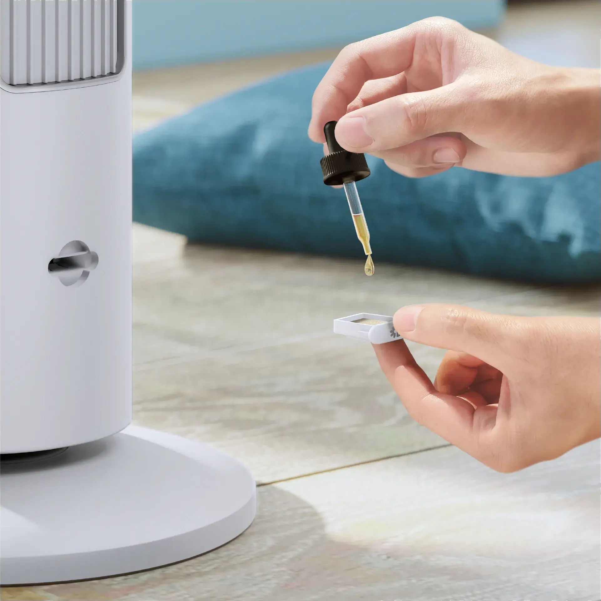 Eine Hand tropft Flüssigkeit aus einer Pipette auf ein kleines weißes Objekt.