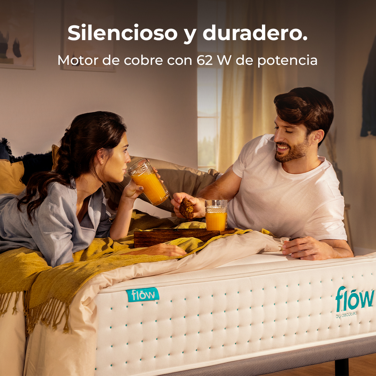 Un hombre y una mujer yacen en la cama bebiendo jugo. Sostienen pasteles.