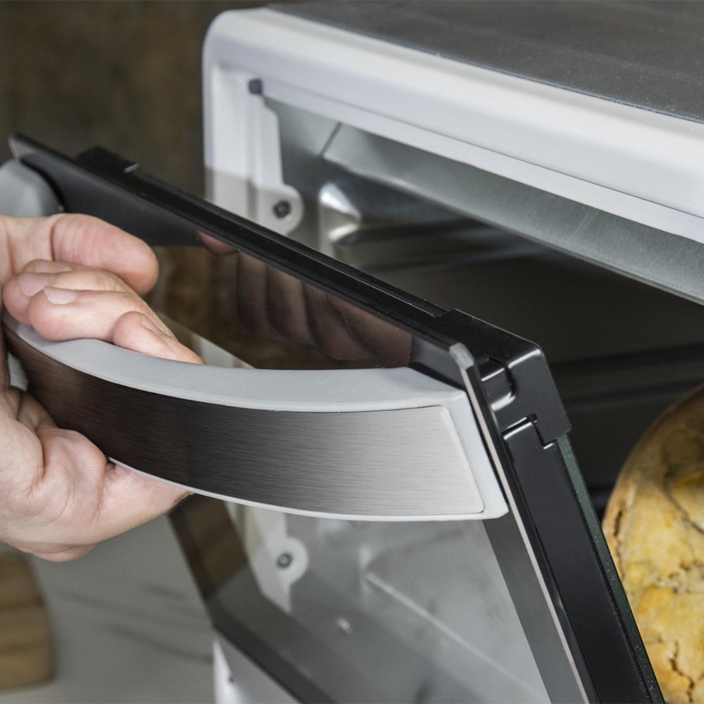 Una mano abre la puerta de un horno con pan dentro.