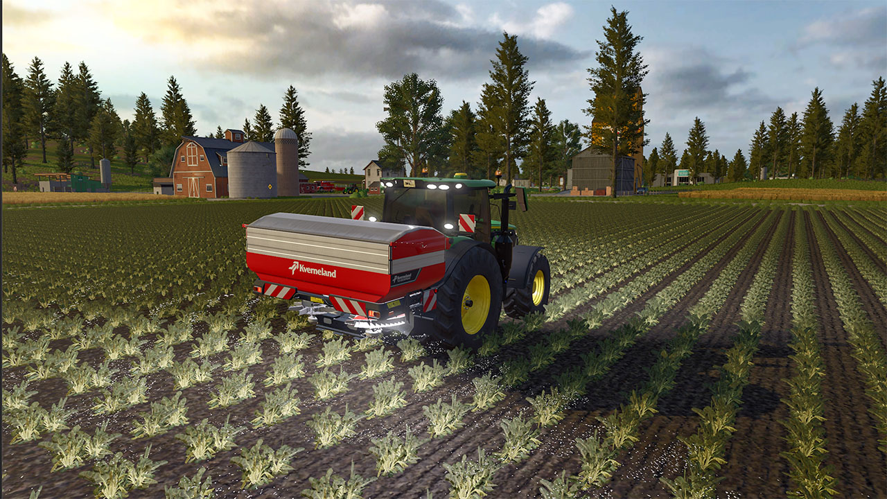 Un tracteur vert avec épandeur d'engrais rouge traverse un champ de jeunes plants.
