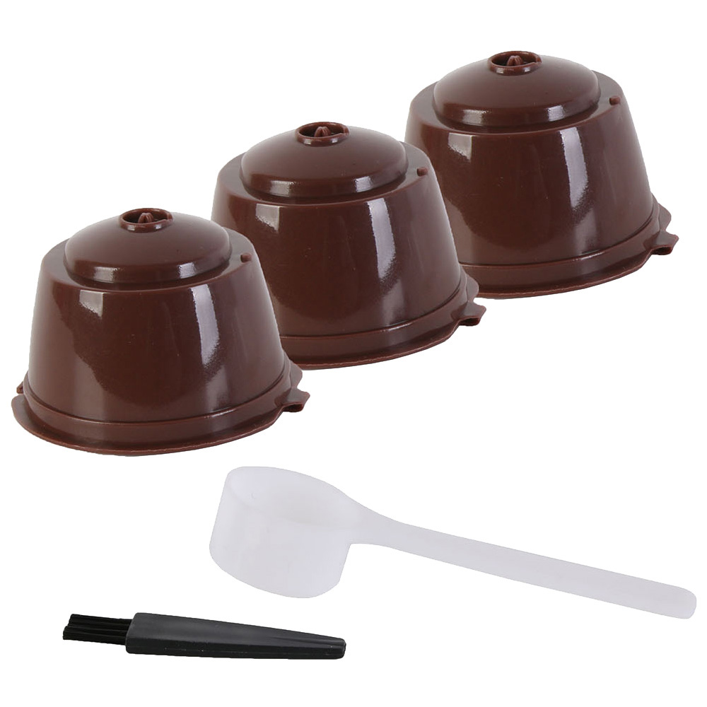 Tres cápsulas de café marrones con una cuchara y un cepillo.
