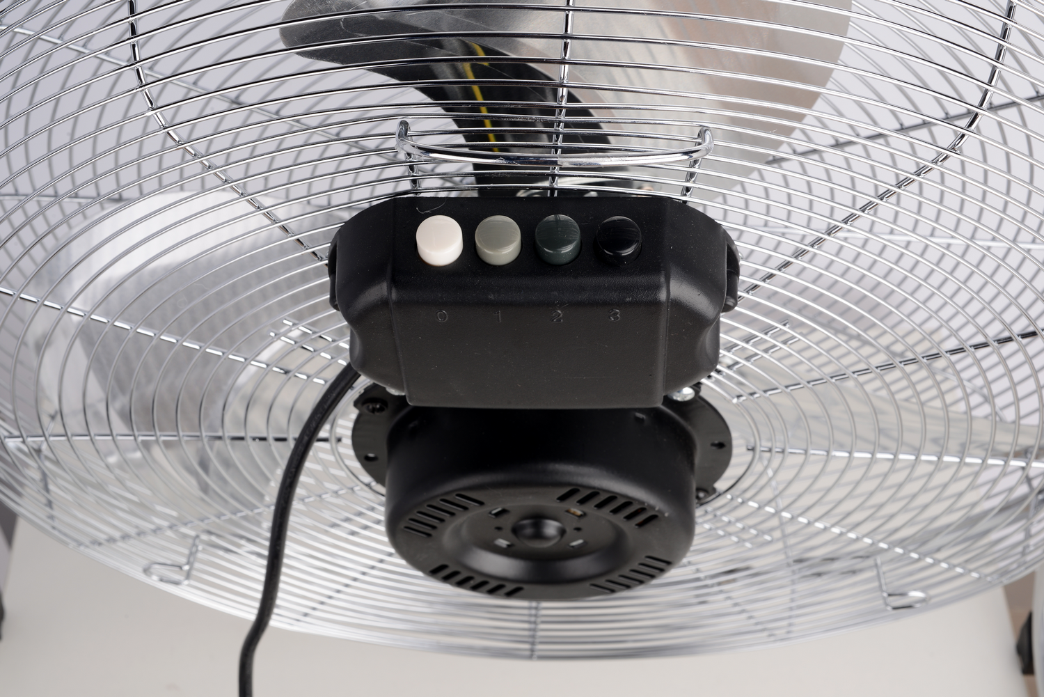 Primer plano de un ventilador plateado con panel de control negro y cuatro botones.