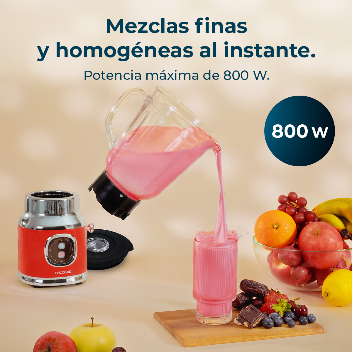 Una batidora roja vierte batido rosa en un vaso. Frutas y chocolate al lado.