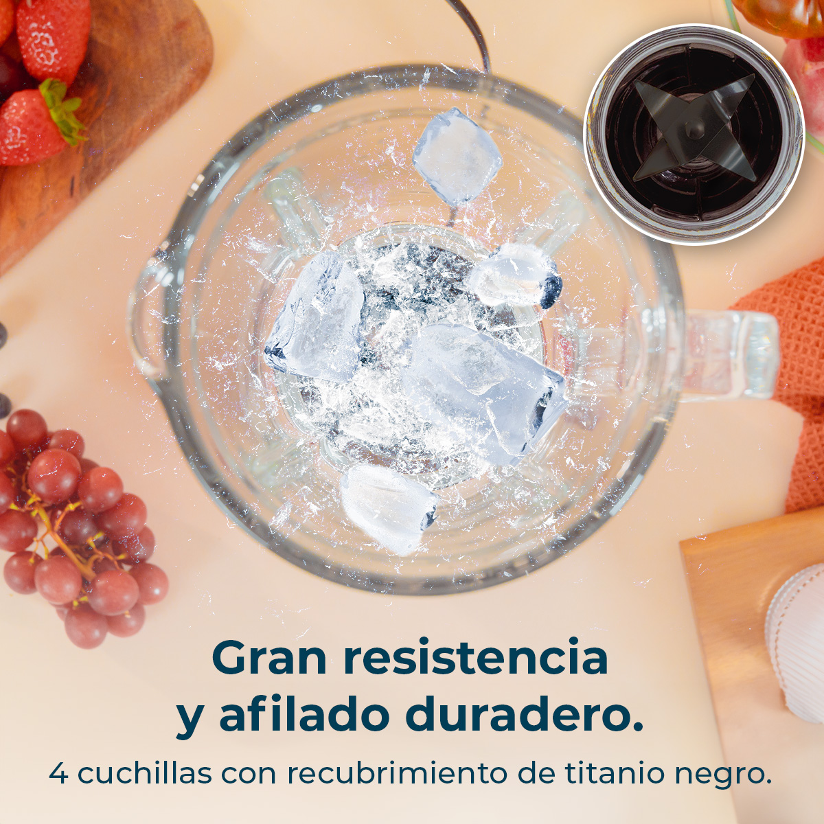 Un vaso de licuadora con cubitos de hielo y agua, junto a fresas y uvas.