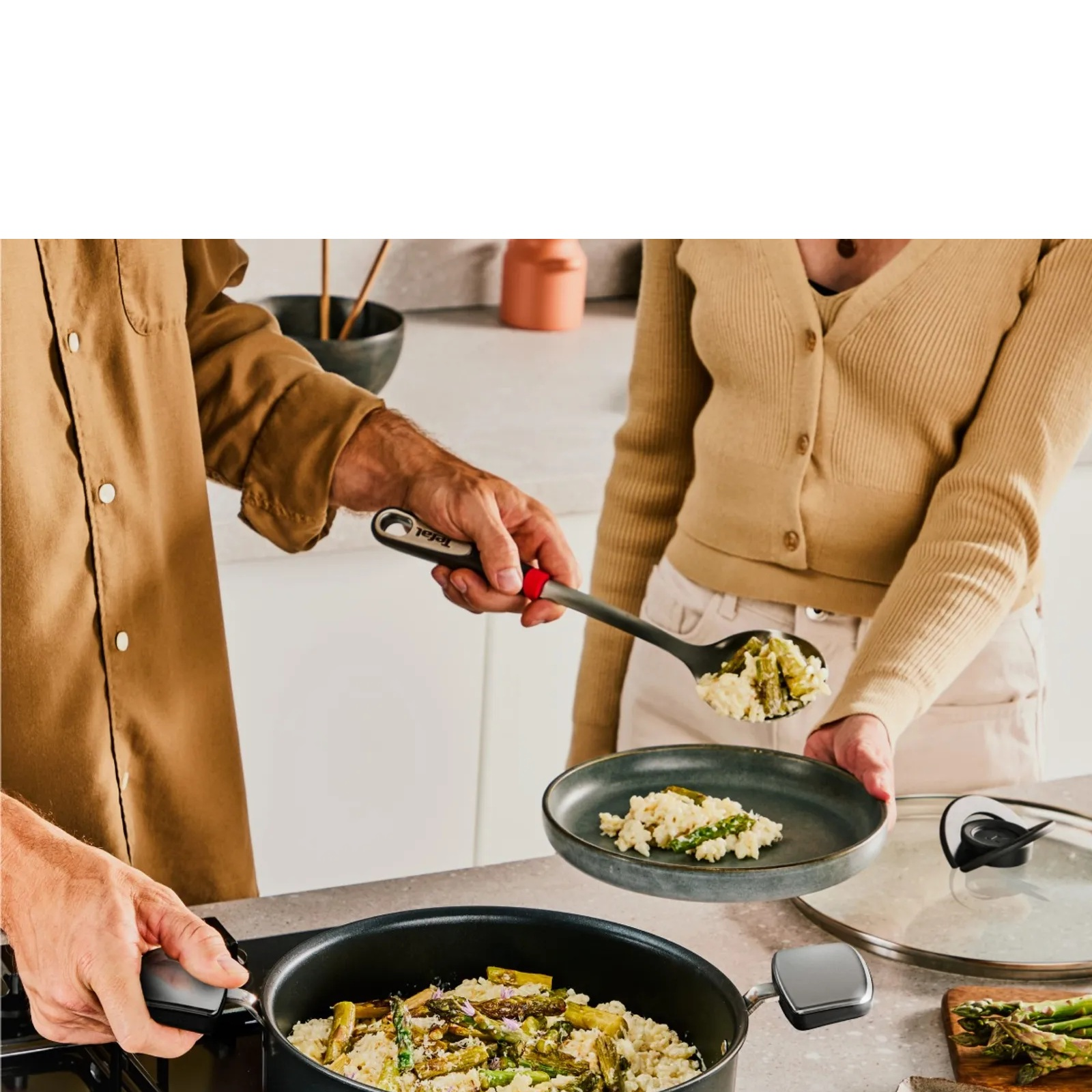 Osoba nakłada risotto z szparagami z garnka na talerz.