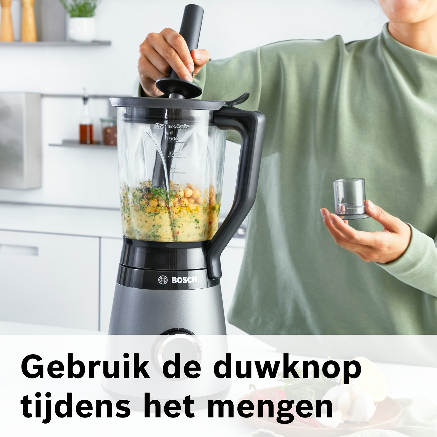 Person mixes ingredients in a blender. A small cap is held.