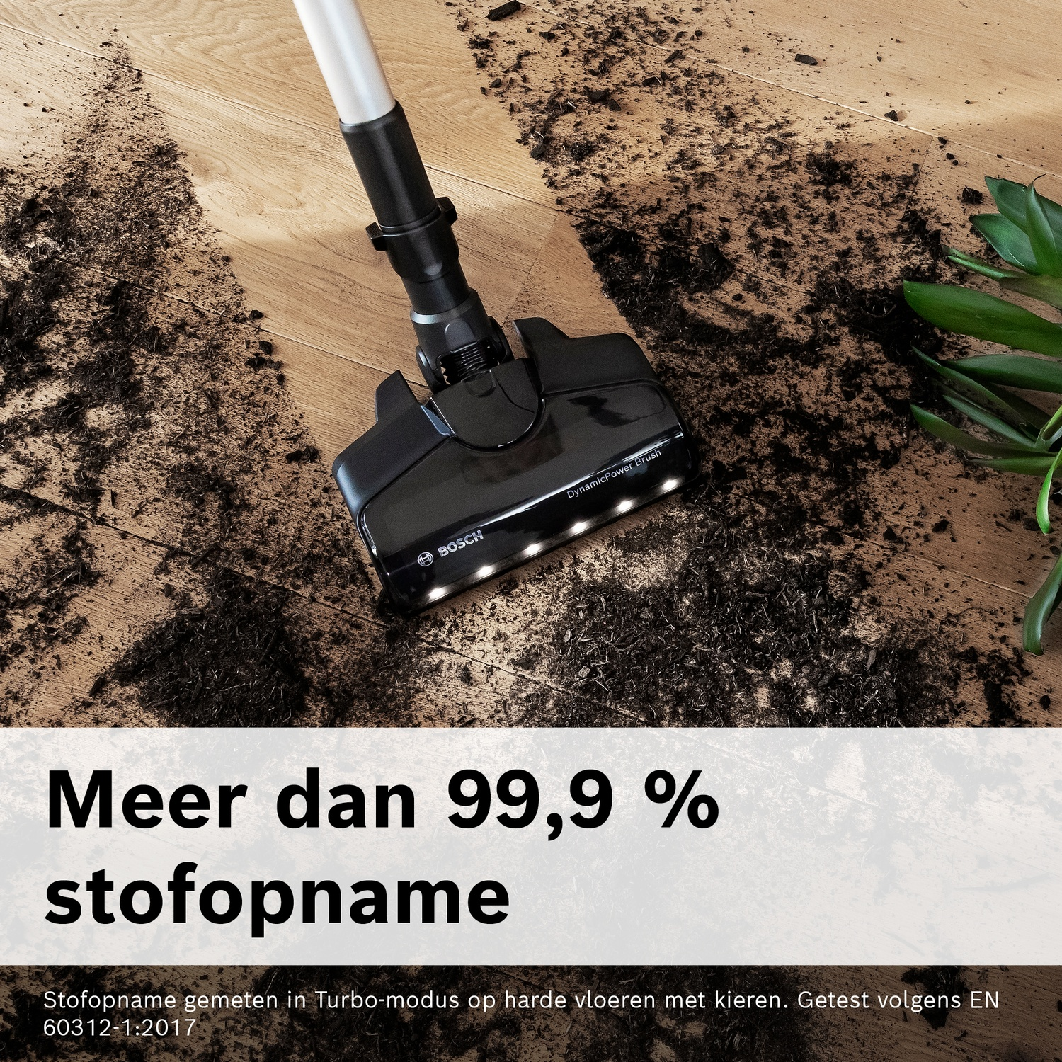 Een zwarte Bosch stofzuigerkop maakt een houten vloer schoon van aarde.