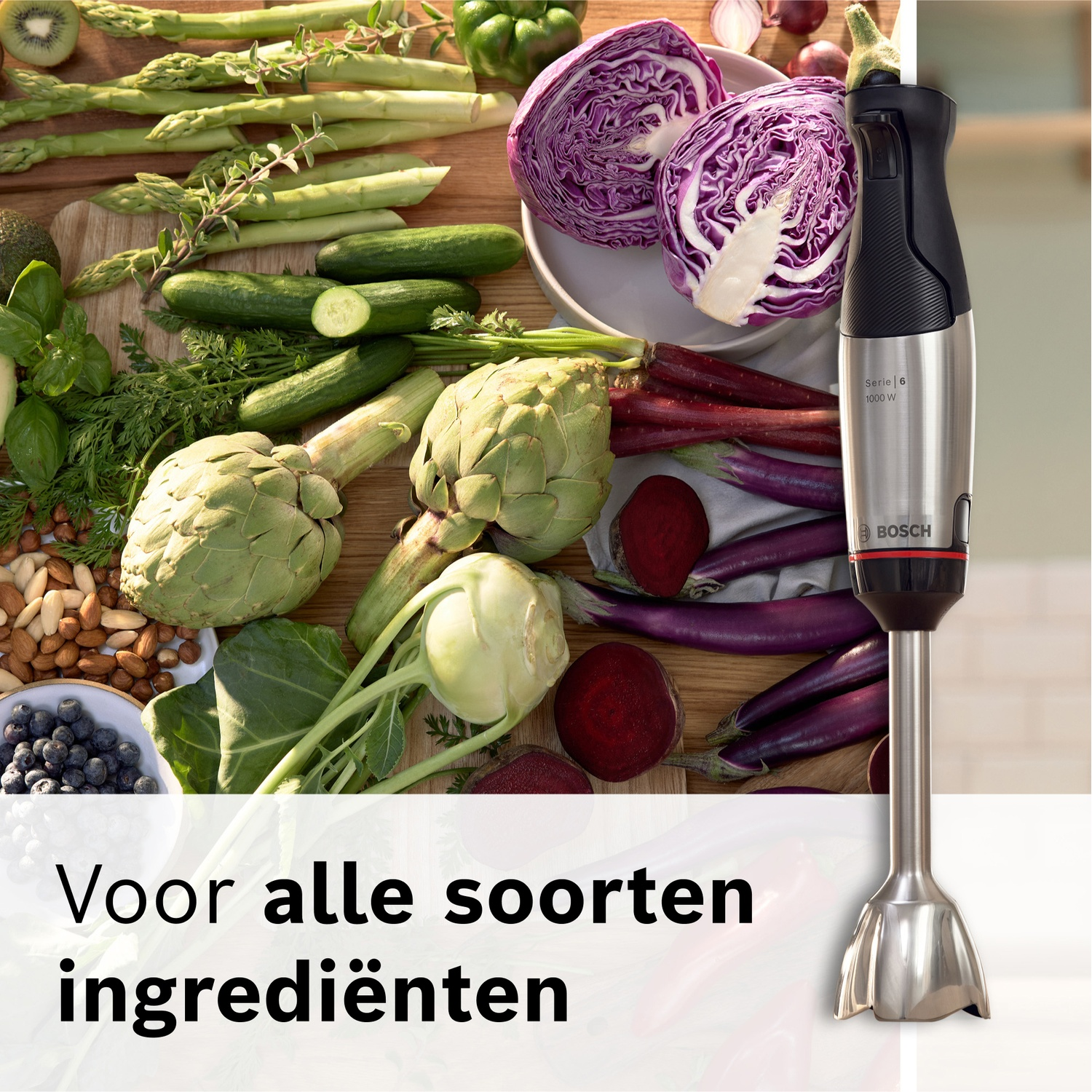 Een staafmixer naast verse groenten zoals asperges, artisjokken en rode kool.