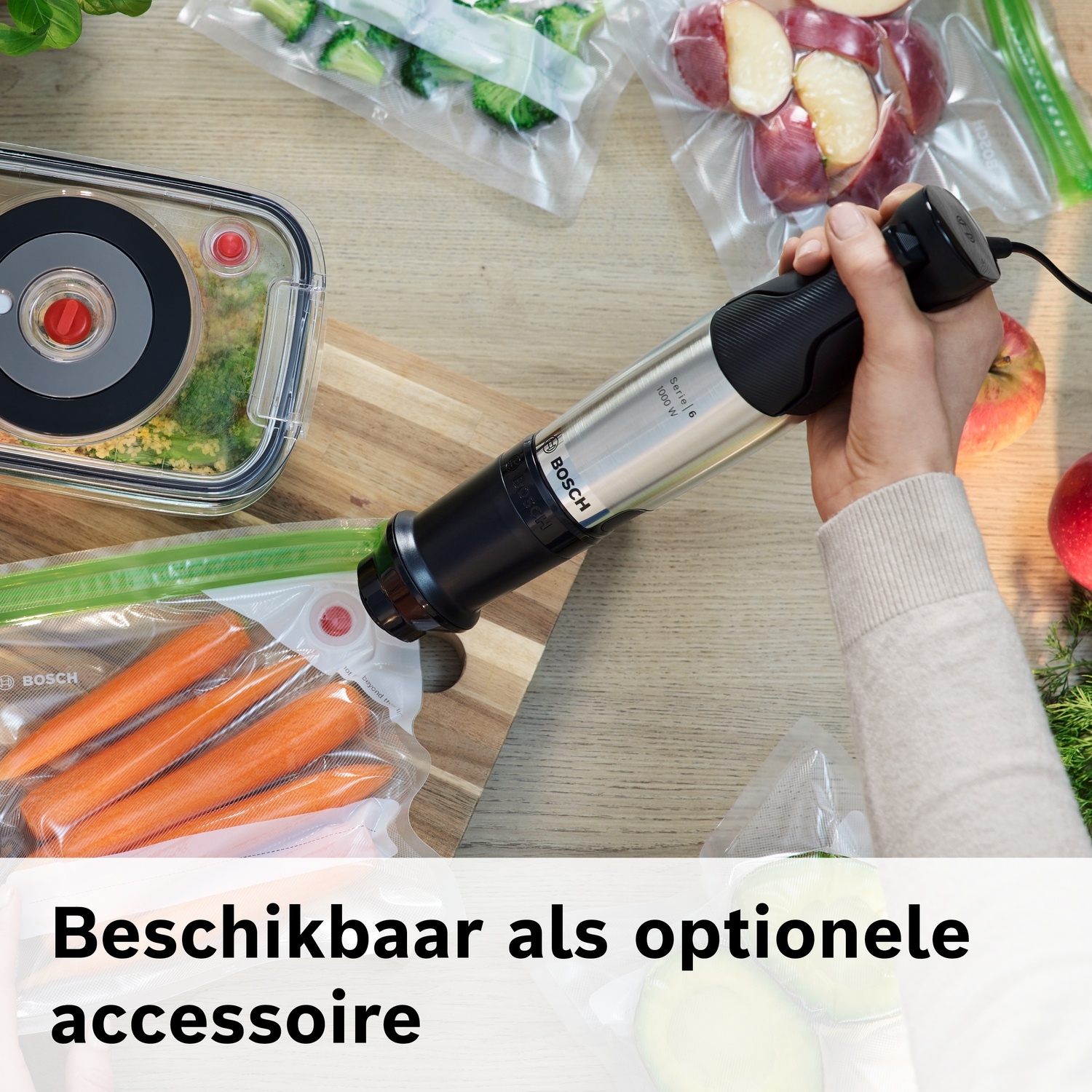 Hand houdt Bosch vacuümmachine boven vacuümzakken met wortels en broccoli.