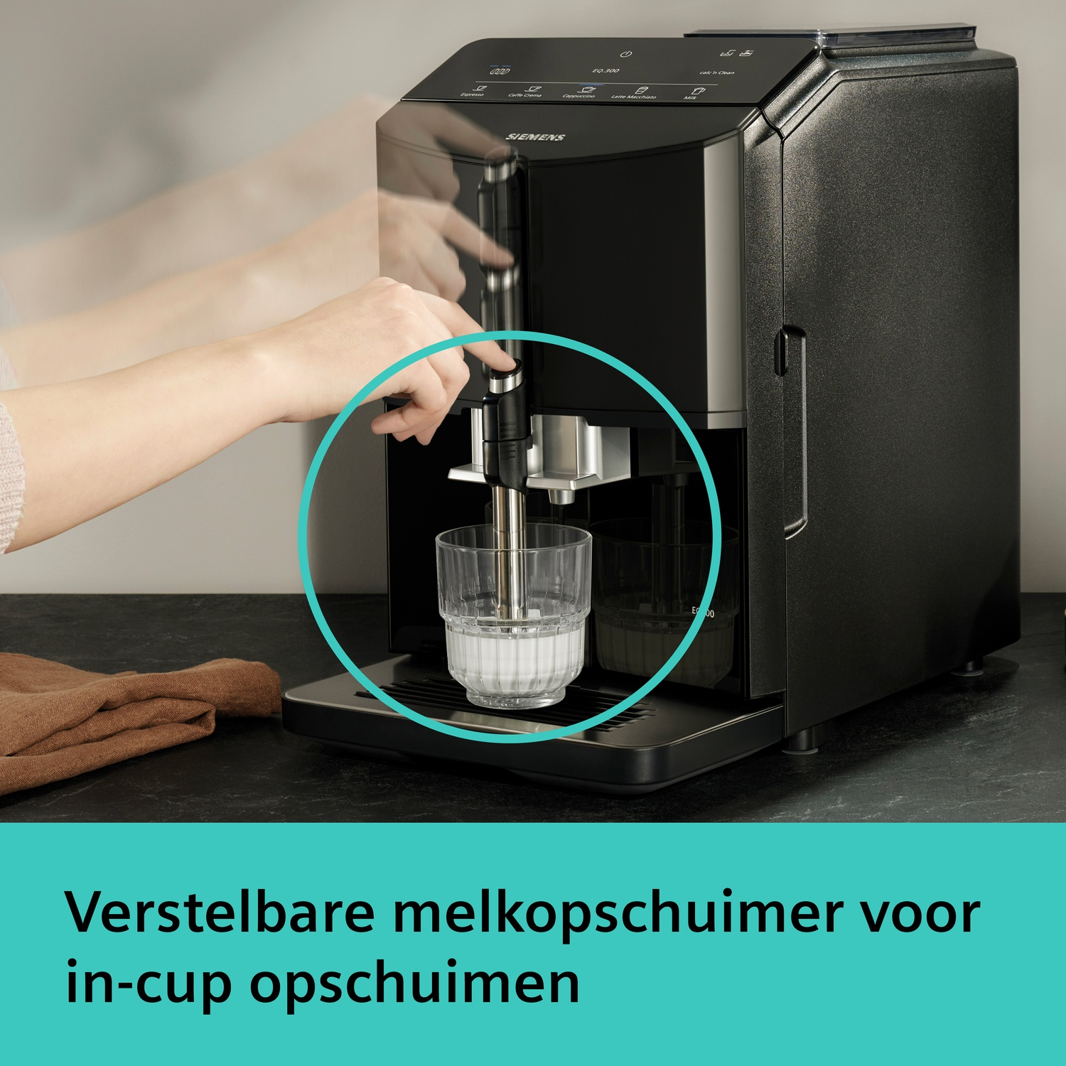 Een persoon bedient een zwarte koffiemachine die melk opschuimt in een glas.
