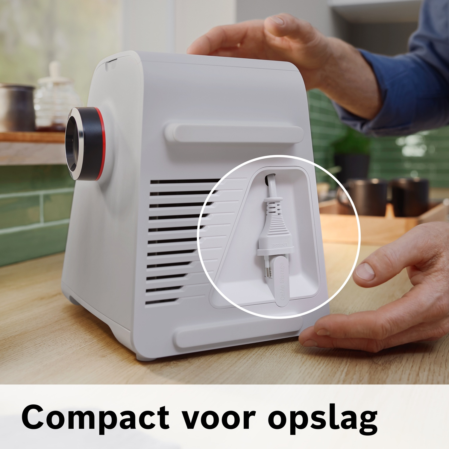 Een man bergt een wit apparaat met een kabel op in een vak.