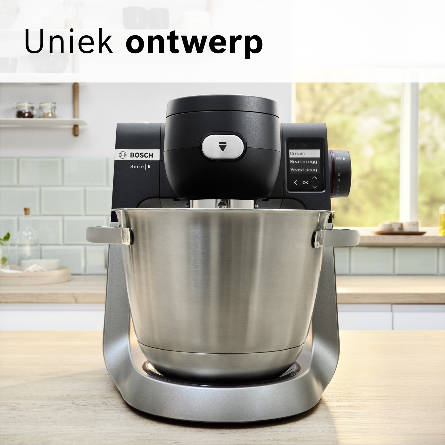 Een zilveren Bosch keukenmixer met zwart opzetstuk en display in een keuken.