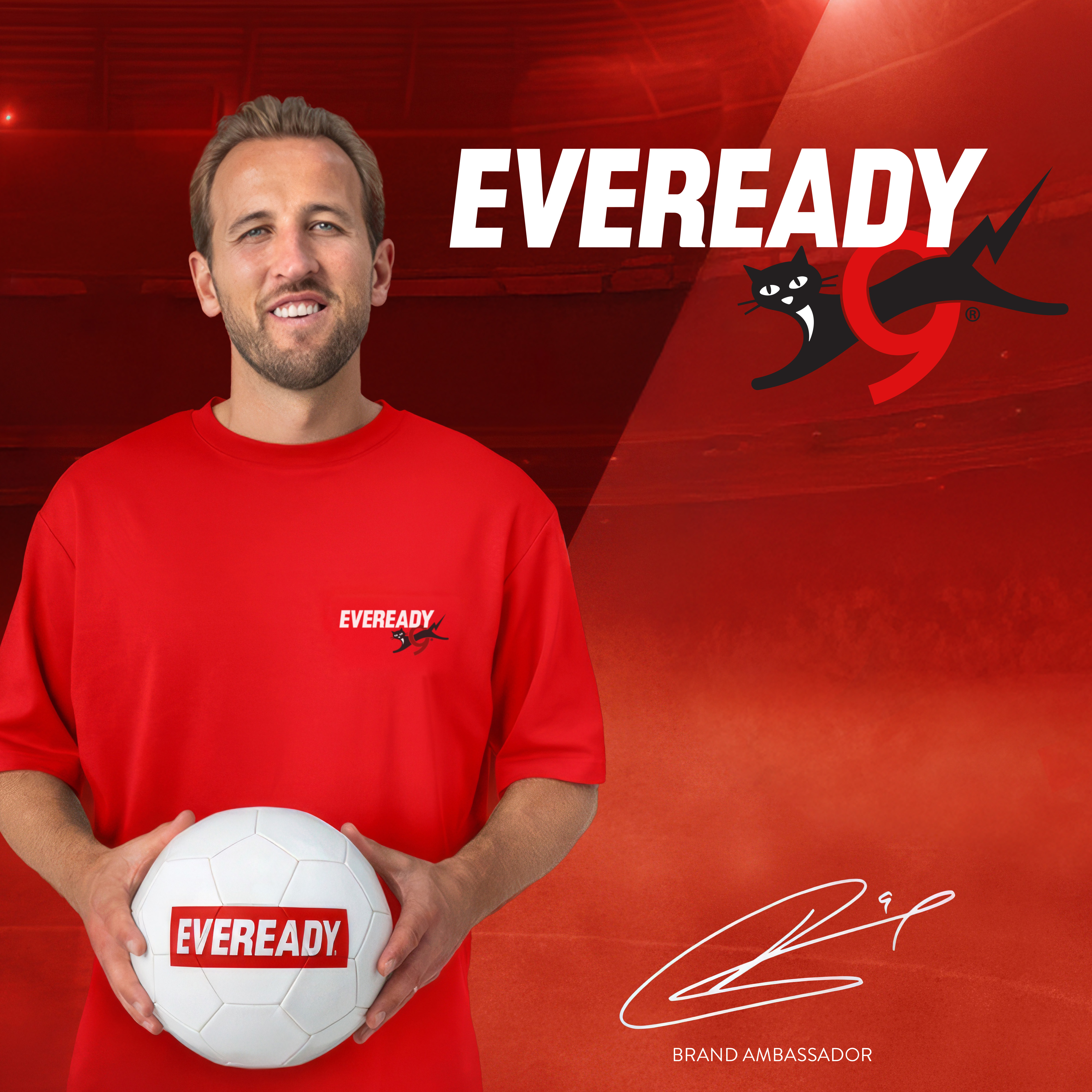 Mann in rotem T-Shirt hält Fußball mit Eveready-Logo vor Eveready-Logo.